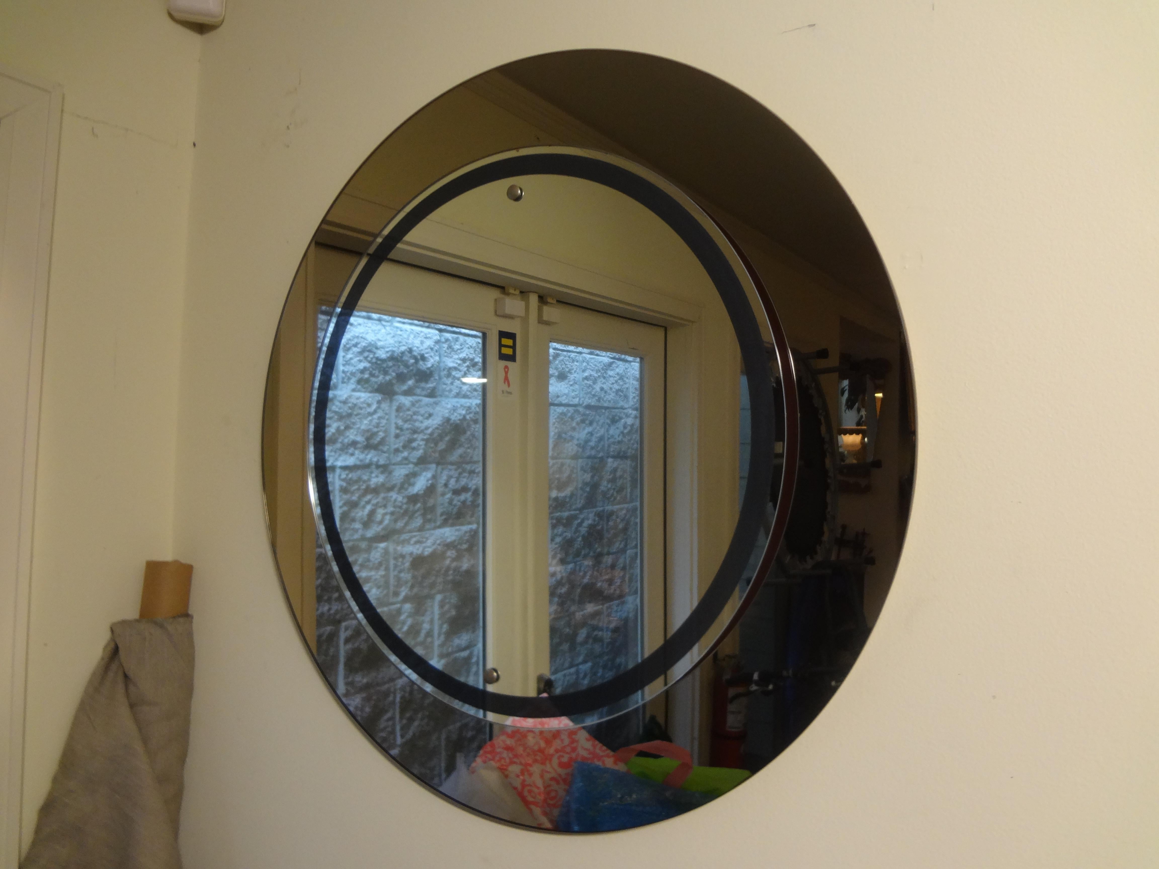 Stunning Italian Fontana Arte inspired round Mid-Century Modern mirror with darker mirror around the perimeter, a circular reverse painted band and chrome accents. This vintage Italian mirror is in very good condition with no chips.