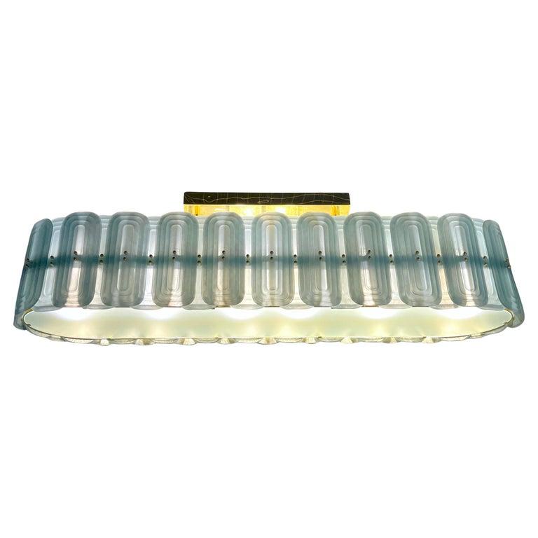 Questo lussuoso lampadario moderno e personalizzabile, ispirato allo stile Fontana Arte, sfoggia un sofisticato design ovale interamente realizzato a mano in Italia. Composto da sofisticati elementi geometrici in vetro di Murano con lavorazione a