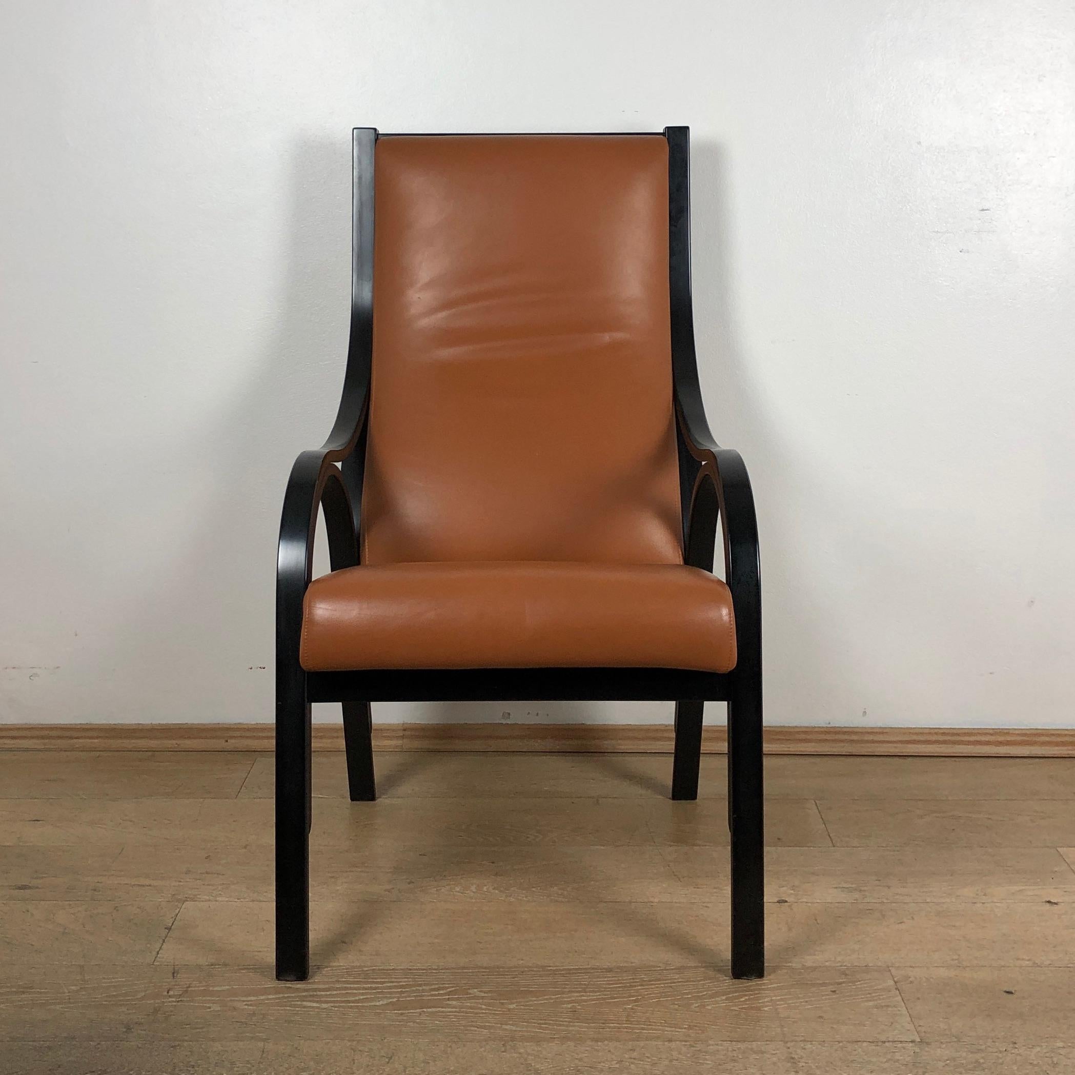 Armchair from 1980s period produced by Poltrona Frau. Structure in curved black lacquered walnut . Backrest and seat shell in beech with polyurethane foam padding upholstered in Pelle Frau® leather . Brand name is found under the seat. This model of