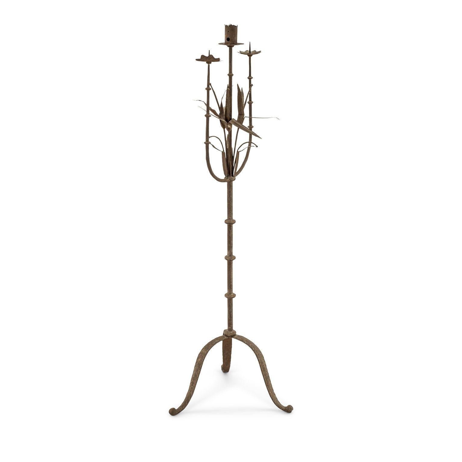 Italian forged iron candelabra dating to the 19th century. Adorned in hammer iron lily motif. Acanthus three-legged base. Nice weathered patina.