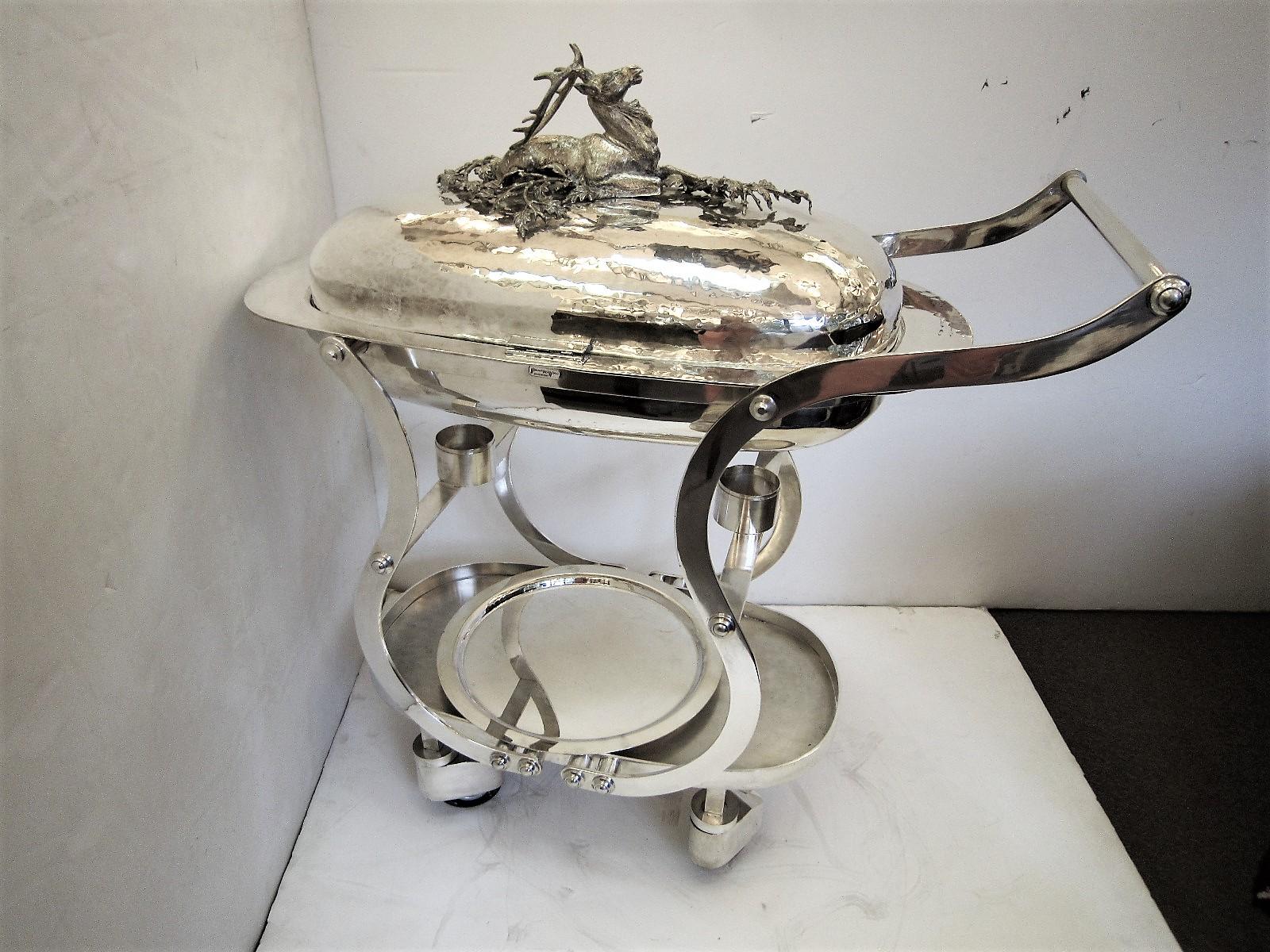 Fabulous Italian oval rolling kitchen with hot water container. Handmade and hand hammered silver plated metal with deer/ elk decoration atop lid, signed Franco Lapini
Can be used for as a serving trolly, for hospitality, a hunting lodge, dining,