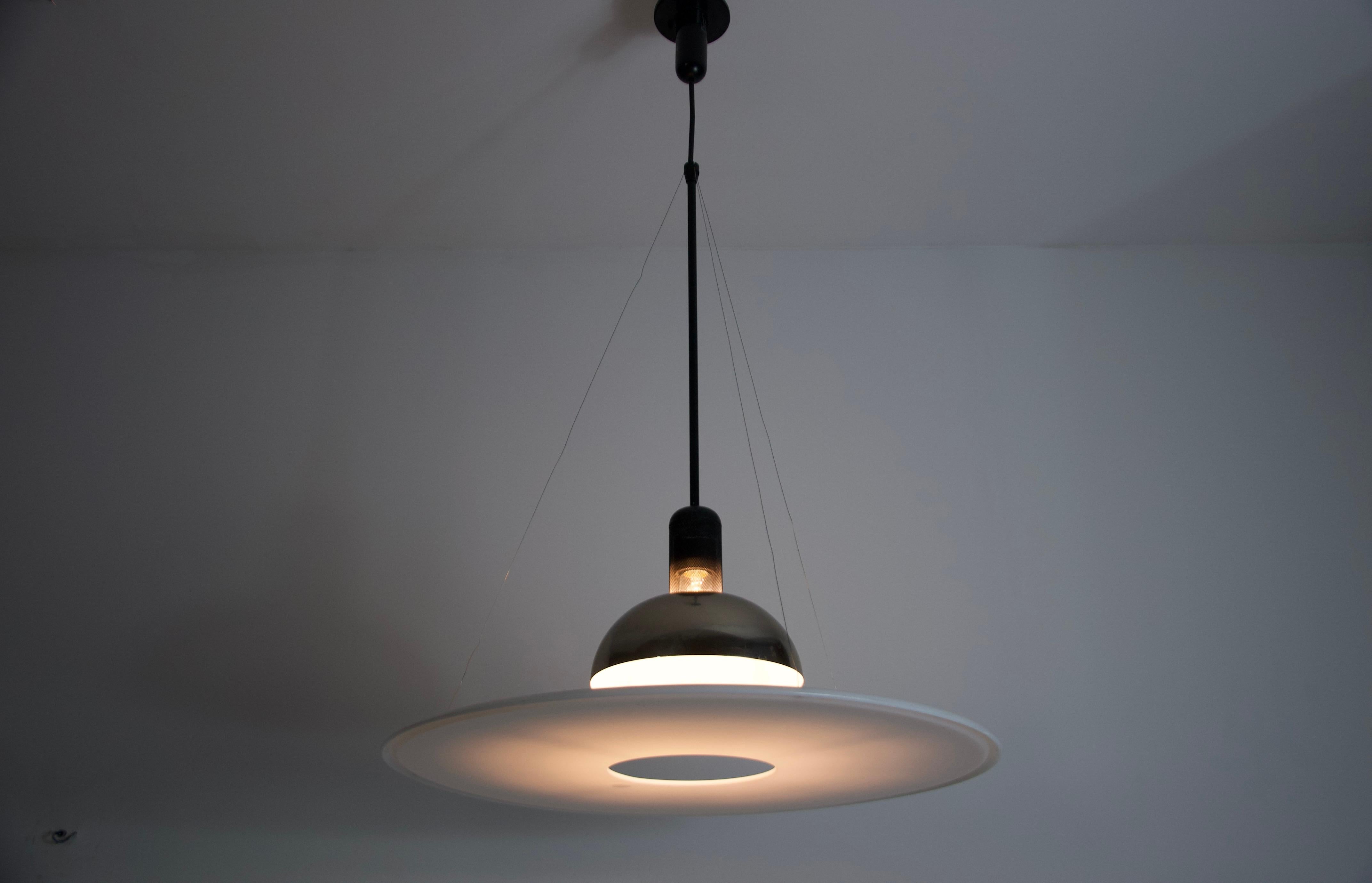The Frisbi 850 pendant lamp, designed by the renowned Italian designer Achille Castiglioni for Flos in the 1970s, is a striking example of minimalist elegance and innovative lighting design. This iconic piece features a suspended acrylic diffuser