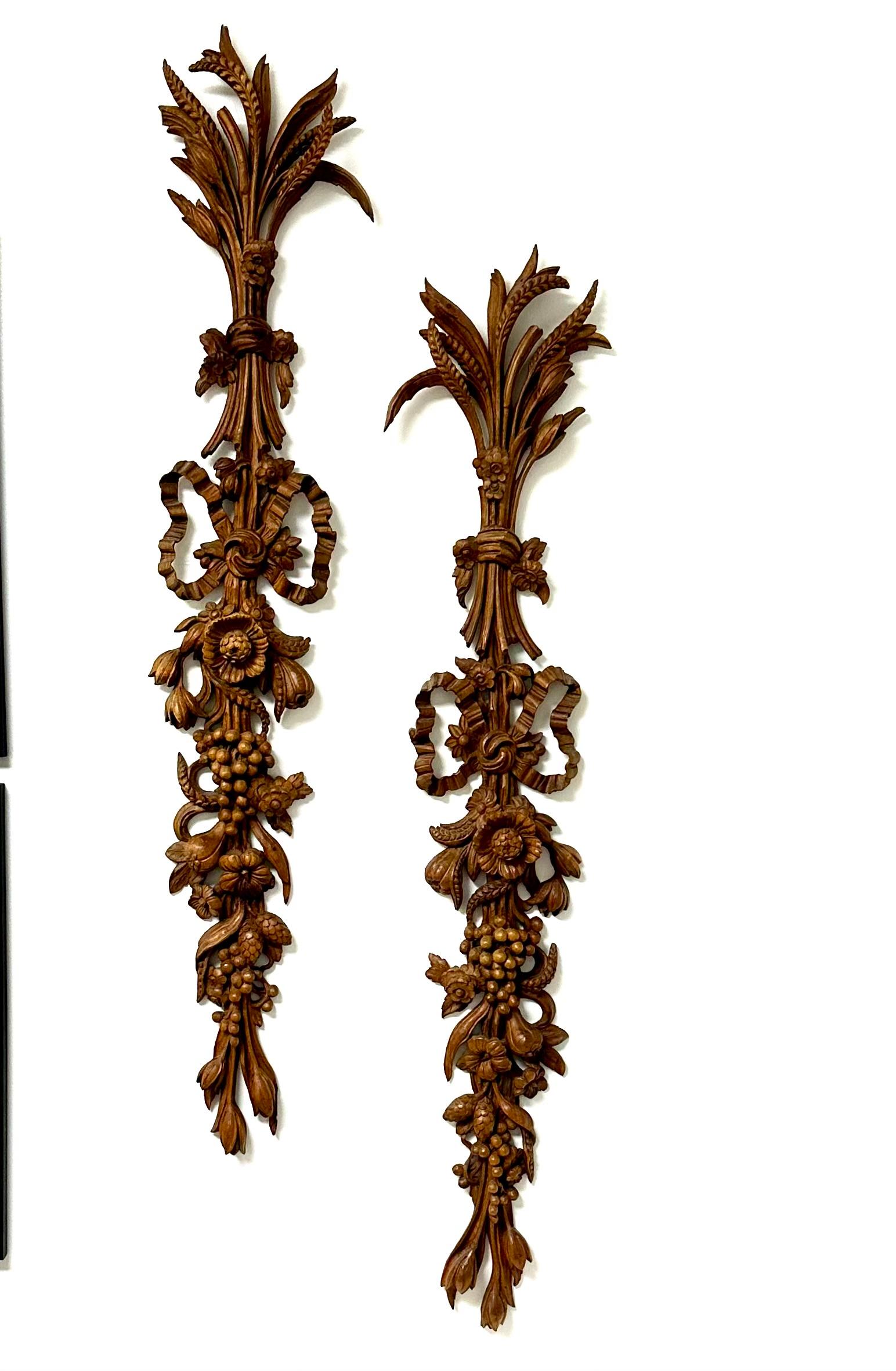 A pair of Fruitwood carved Italian bouquet of flowers wall hangings. With wheat grapes and assorted other fruit, eight types of flowers and a large bow. Each with old tags on the back. Circa 1890s .They have a couple of chipped leaves here and