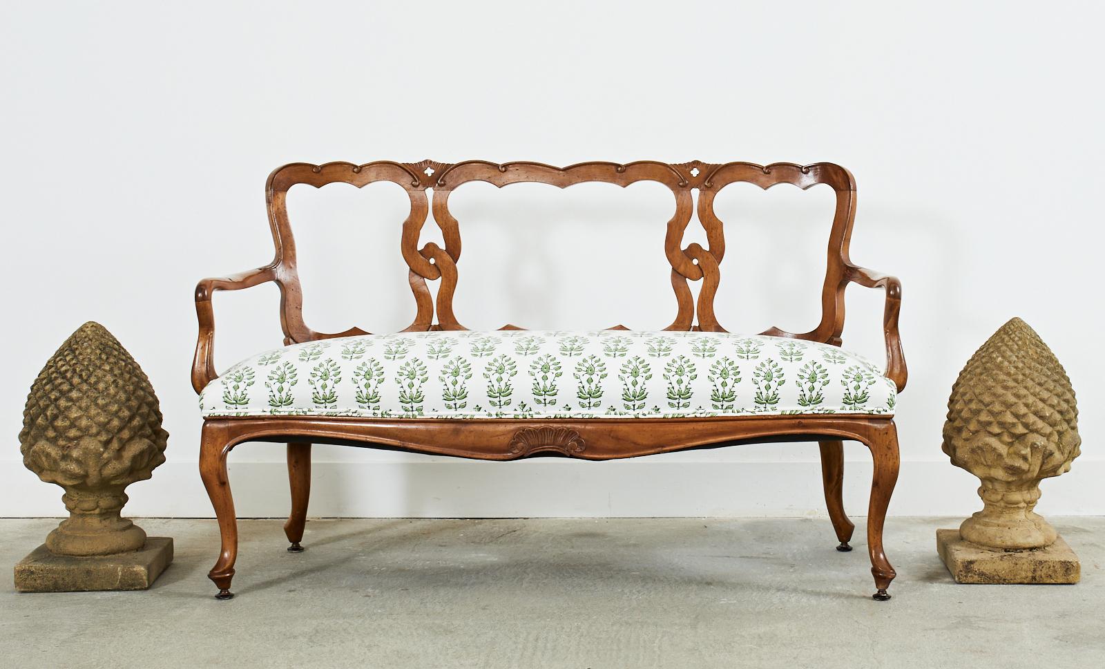 Gorgeous Italian fruitwood settee or bench carved in the Venetian style. Features an interlocking design on the back decorated with small scrolls and quatrefoils. The arms measure 25.5 inches high and conjoin to a generous seat with curved ends and