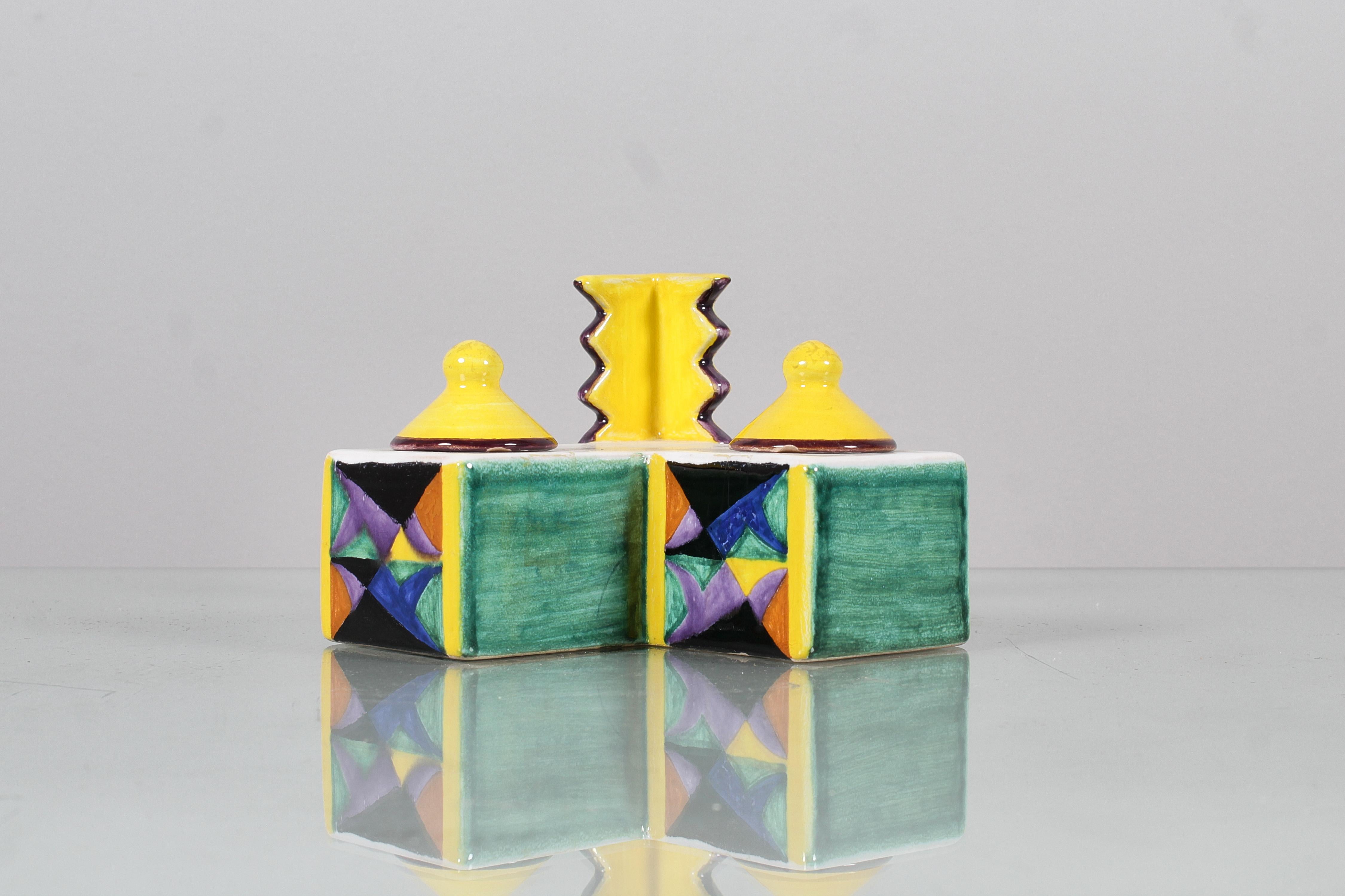 Calamaio per due inchiostri dall'accattivante design futuristico, riedizione della creazione basata su un disegno dell'illustre esponente futurista Pippo Rizzo del 1929. Ceramica interamente dipinta a mano con motivi geometrici policromi. In basso