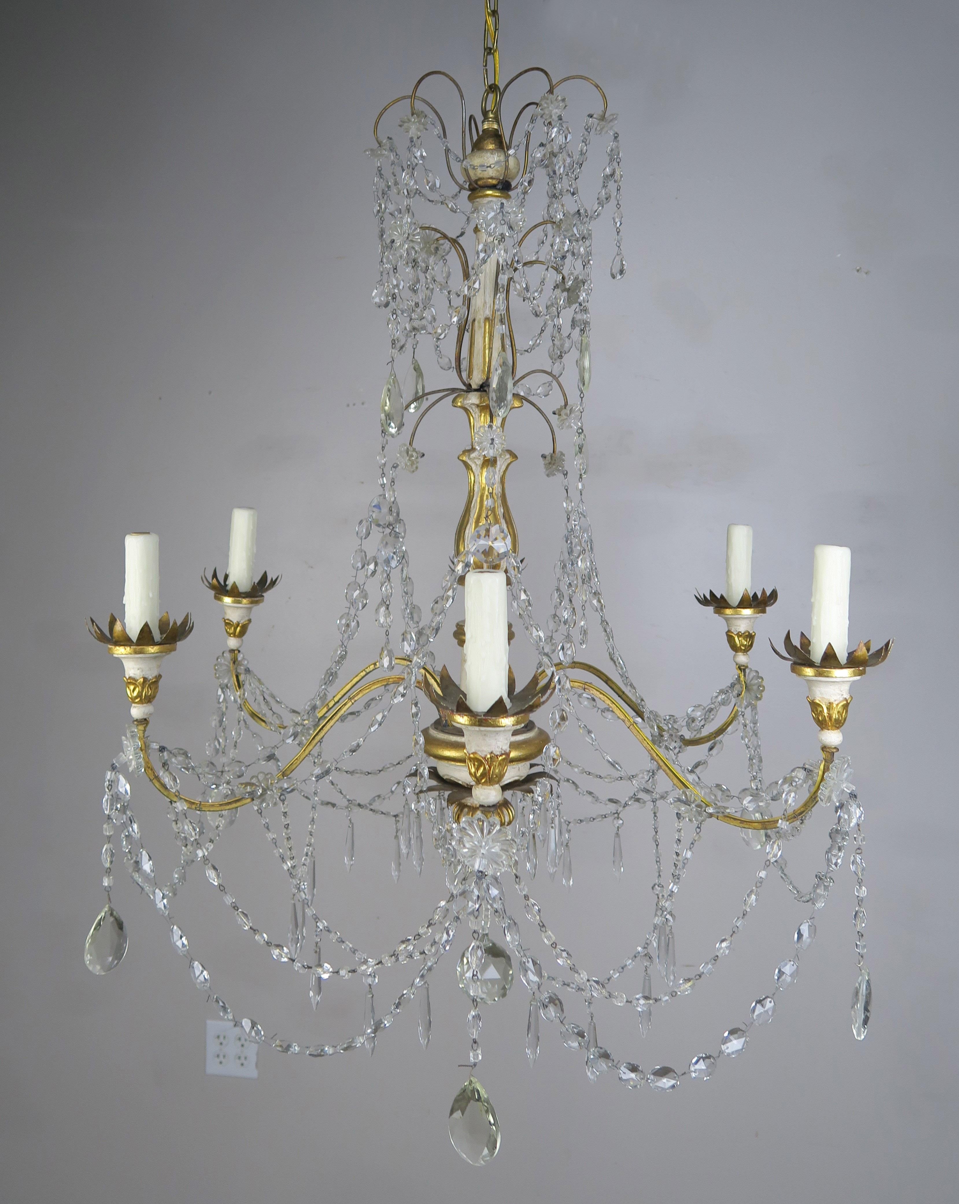 Italian Geneviere style six light painted & parcel gilt crystal chandelier with wrought iron flower shaped bobeches. The fixture is newly rewired with cream colored drip wax candle covers.