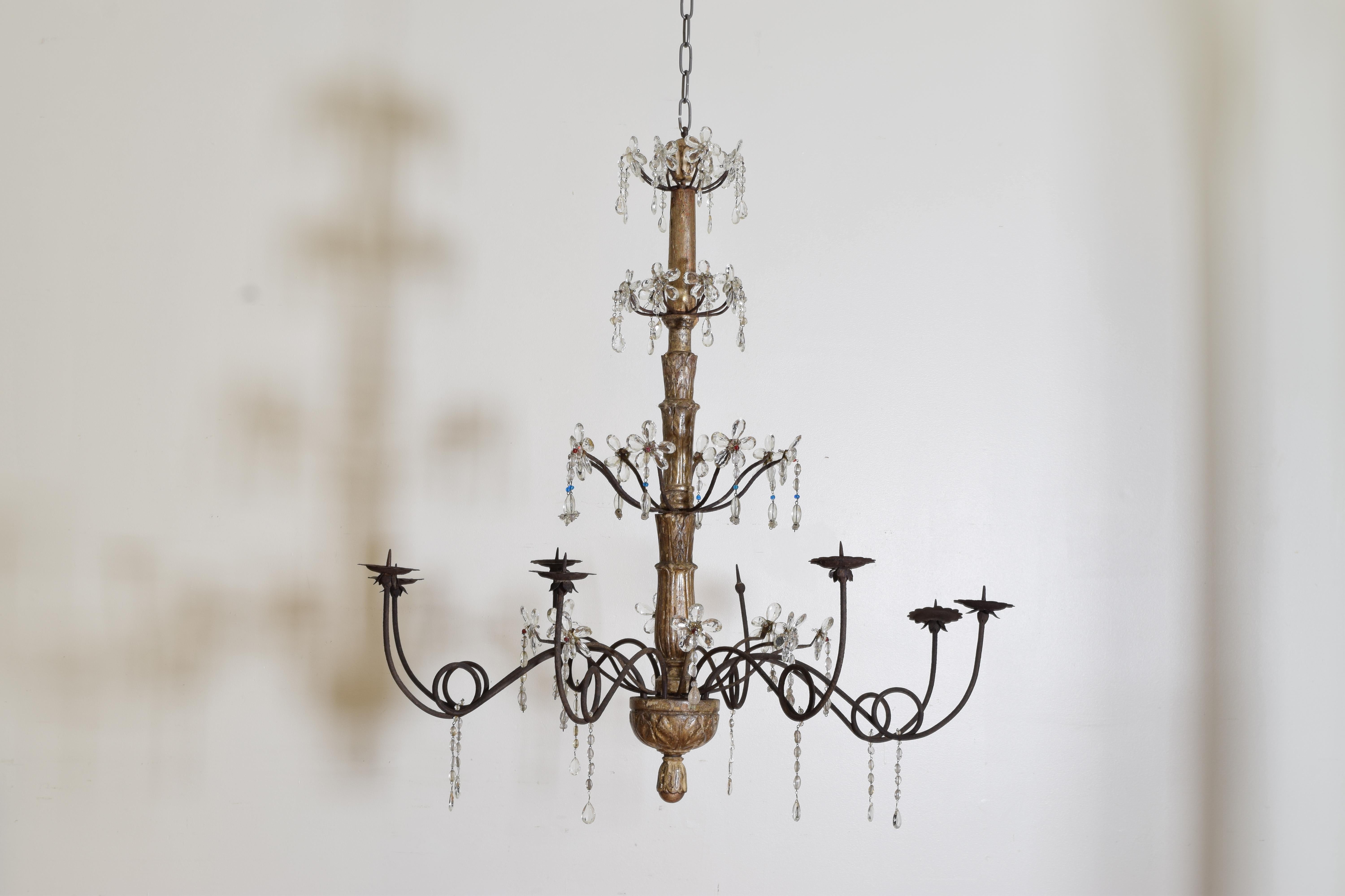 Constructed of a tapering carved standard, the sections divided by iron arms issuing from the circular dividers, the arms decorated with glass flowers made up of teardrop shaped prisms with some colored glass accents