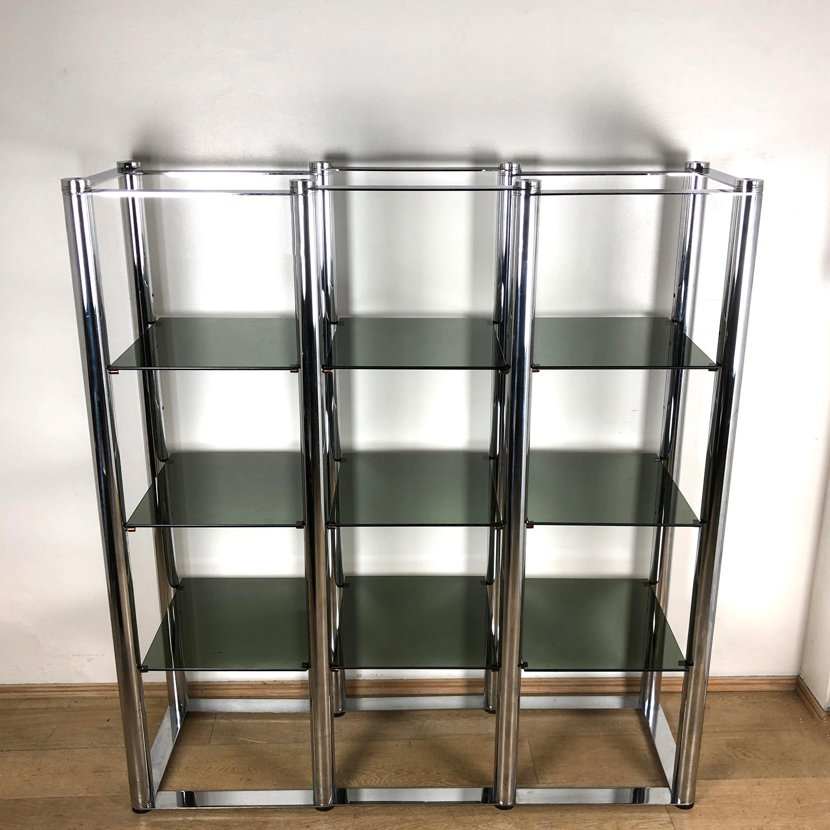 Squared vintage bookcase or étagère with steel structure and removable and adjustable smoked glass shelves. The Vertical structural bar are rounded while the horizontal bare are plated. If you look at this book case standing in front of it you see