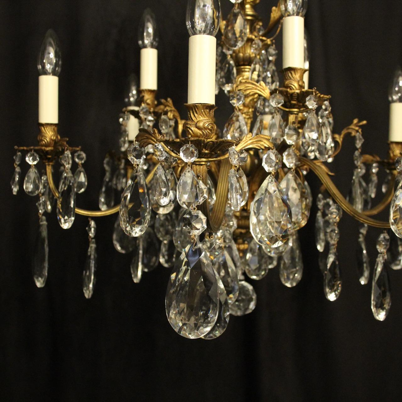 An Italian gilded bronze and crystal 12 light double tiered antique chandelier, the acanthus leaf scrolling arms with leaf bobeche drip pans and bulbous candle sconces, issuing from an ornately cast central column with leaf canopy, decorated overall