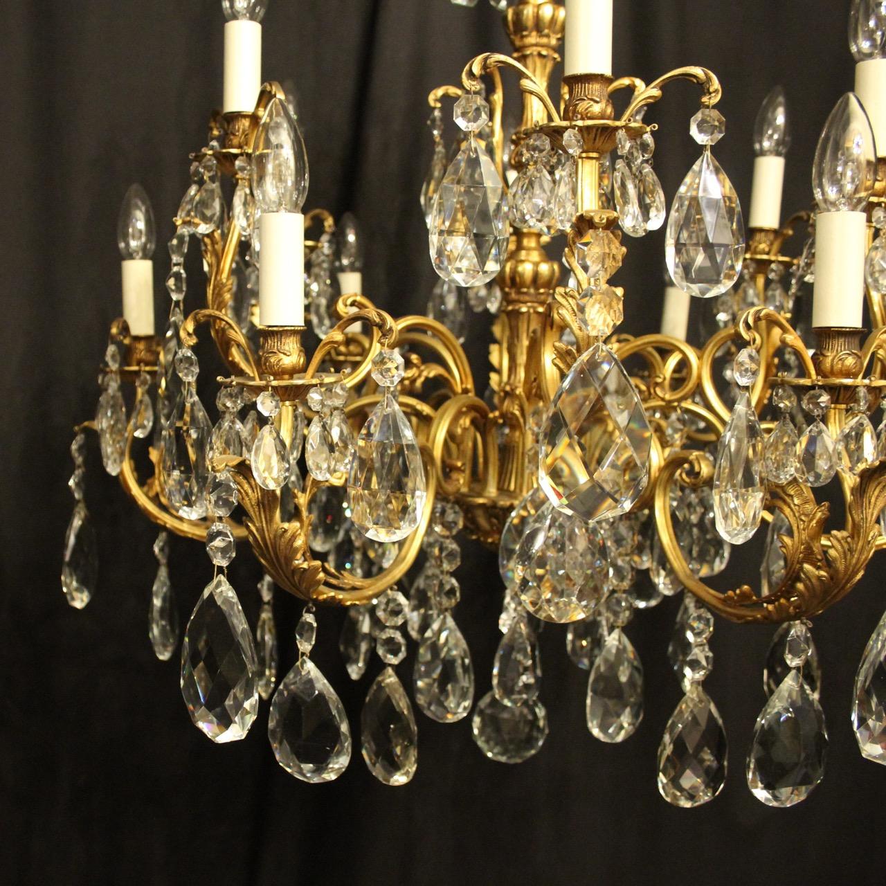 A quality Italian gilded bronze and crystal 12-light double tiered antique chandelier, the ornately cast leaf scrolling arms with leaf bobeche drip pans and bulbous candle sconces, issuing from a foliated central column with leaf scrolling canopy,