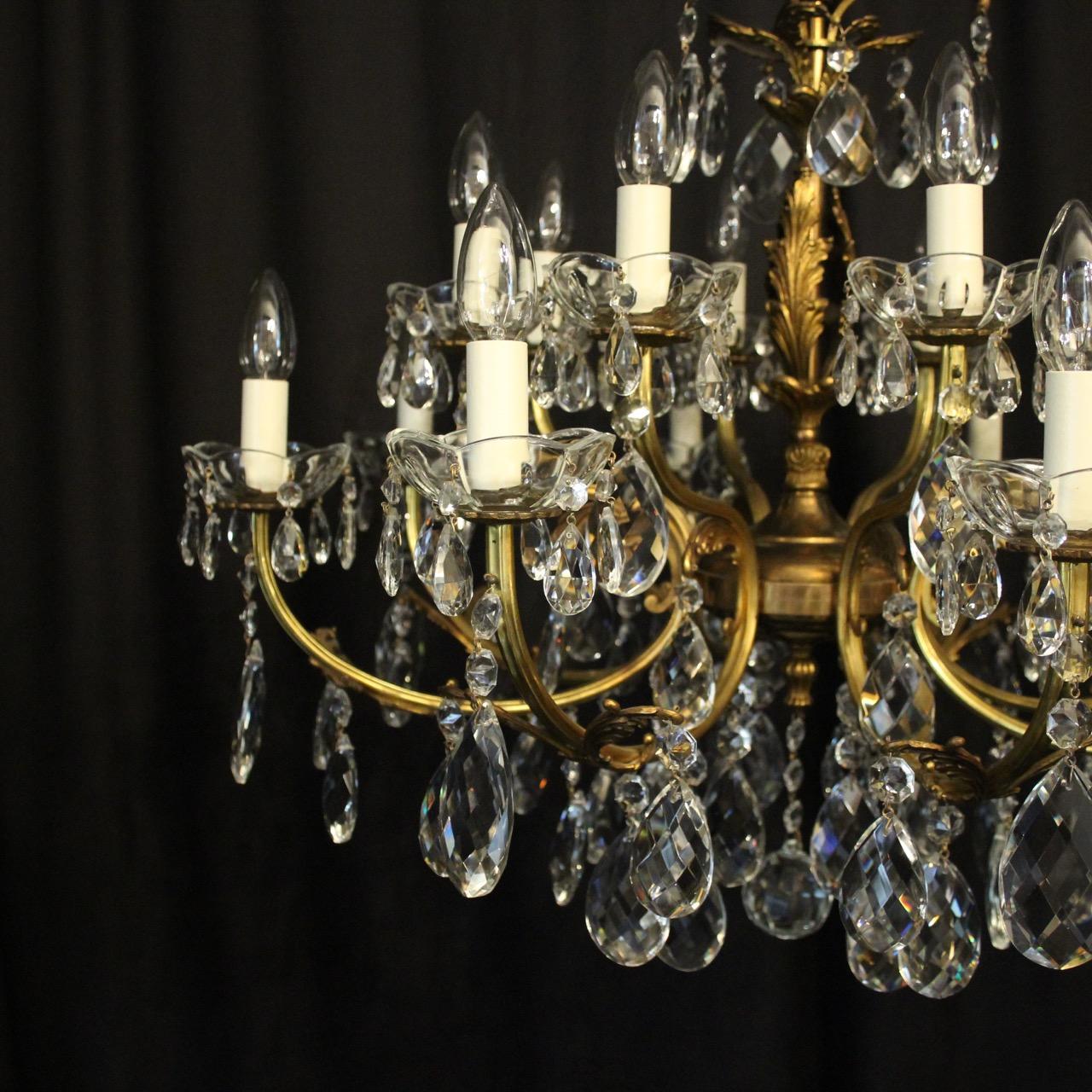 An Italian gilded brass and crystal 16-light double tiered antique chandelier, the leaf scrolling arms with Acanthus leaf outcrops and crystal bobeche drip pans, issuing from a triple leaf pierced central column with a foliated leaf canopy,