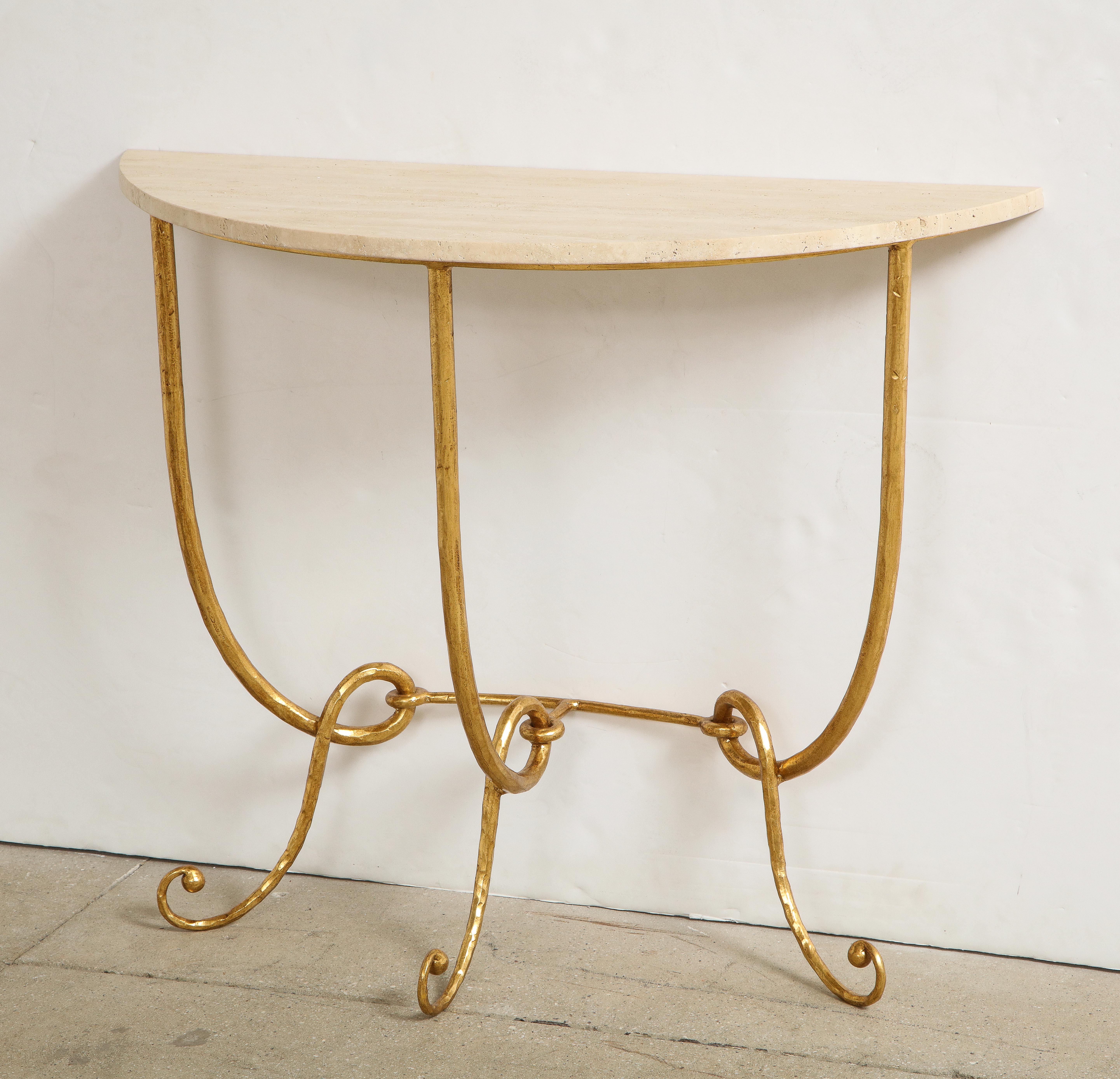 An Italian 1970s gilded iron demilune console table with travertine top. The handcrafted iron having a gilded finish decorated with scrolled legs. The legs are conjoined with a cross stretcher. The organic travertine provides a wonderful contrast