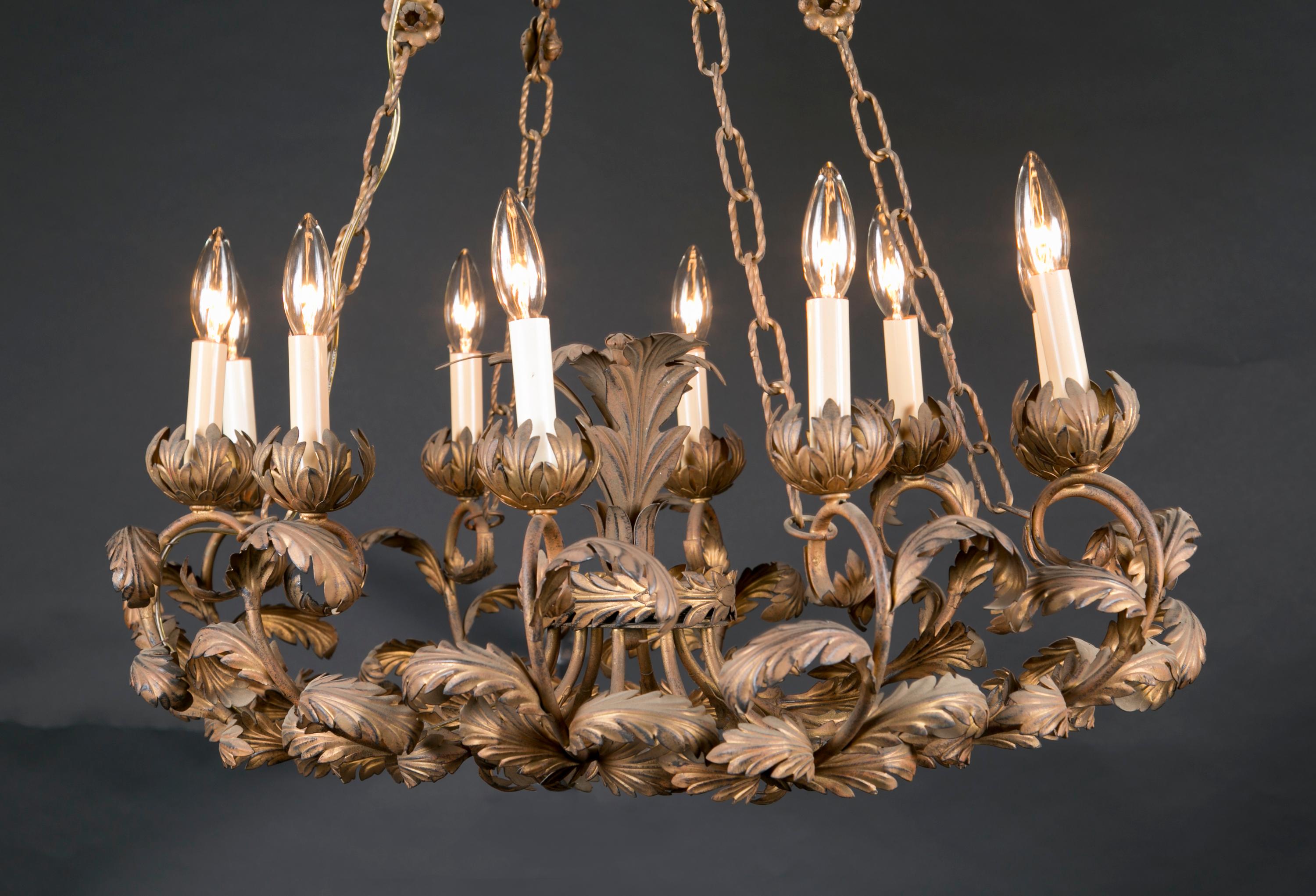 This beautiful floriate Italian chandelier is made of gilded (gold leaf covered) tole and features a forest of leaf bobeches as well as ten (10) lights. The oval fixture dates back to the mid 20th century and is suspended by four chains from a