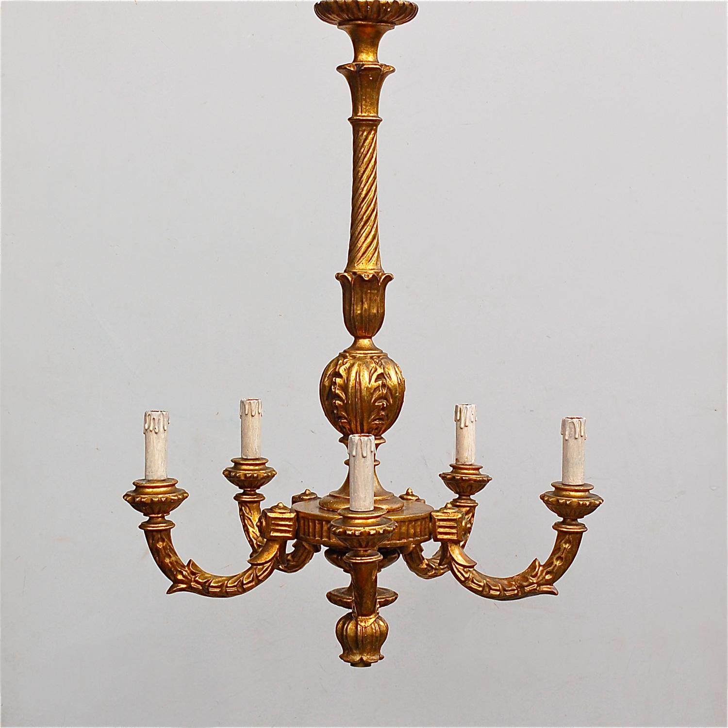 Early 20th century carved wooden chandelier, painted in a warm, antique gold creating an ormolu style effect. It has a slender central column with rounded gallery at the based ending in a carved wooden flower shaped bulb holder. Five curved wooden