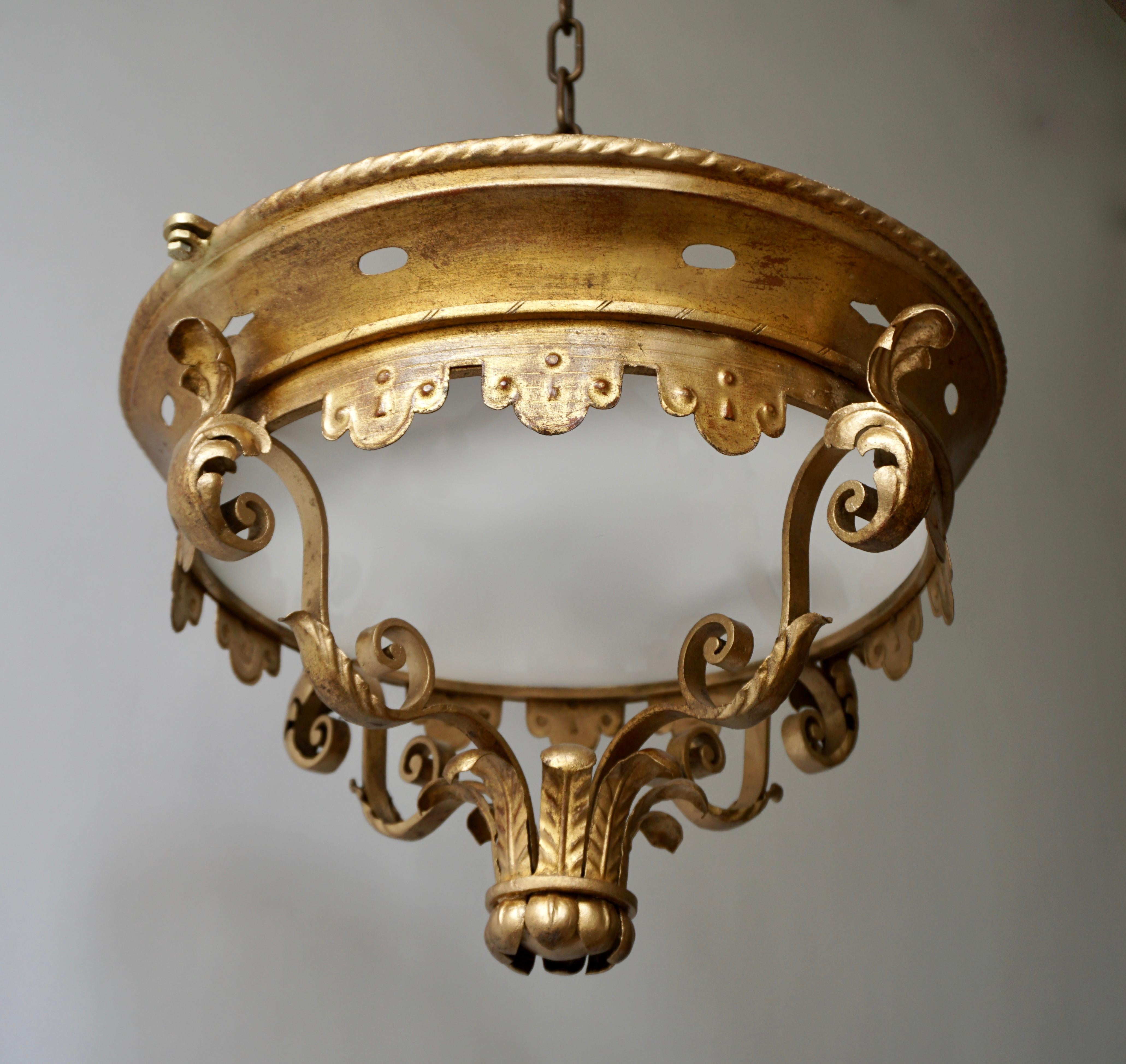 Mid-Century Modern gilt iron crown sunburst flush mount /pendant with leaf motifs surrounding a central frosted glass diffuser. Italy, 1950s handcrafted in hand-hammered iron. Beautiful to be placed in a main room, big entry or in a large corridor