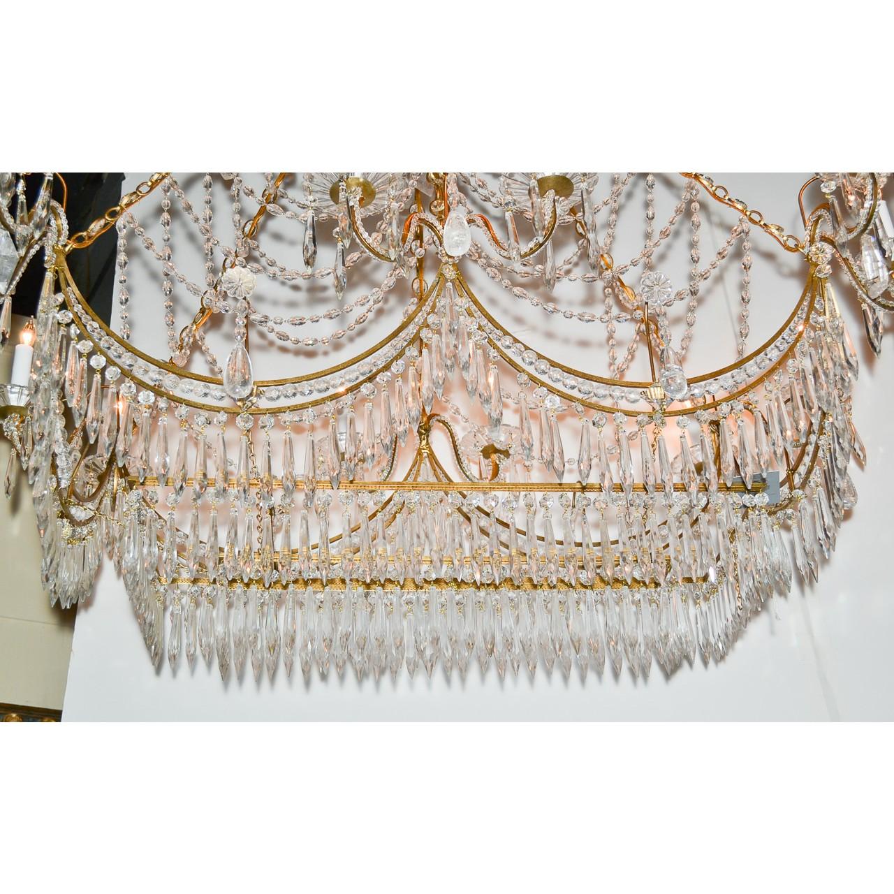 A most unique Italian gilt brass and crystal elongated chandelier. The crown adorned with icicle and pear-shaped prisms atop an abundance of cascading bead cut crystals, and scrolling arms with flower-petal bobeche. The base lavishly draped with a