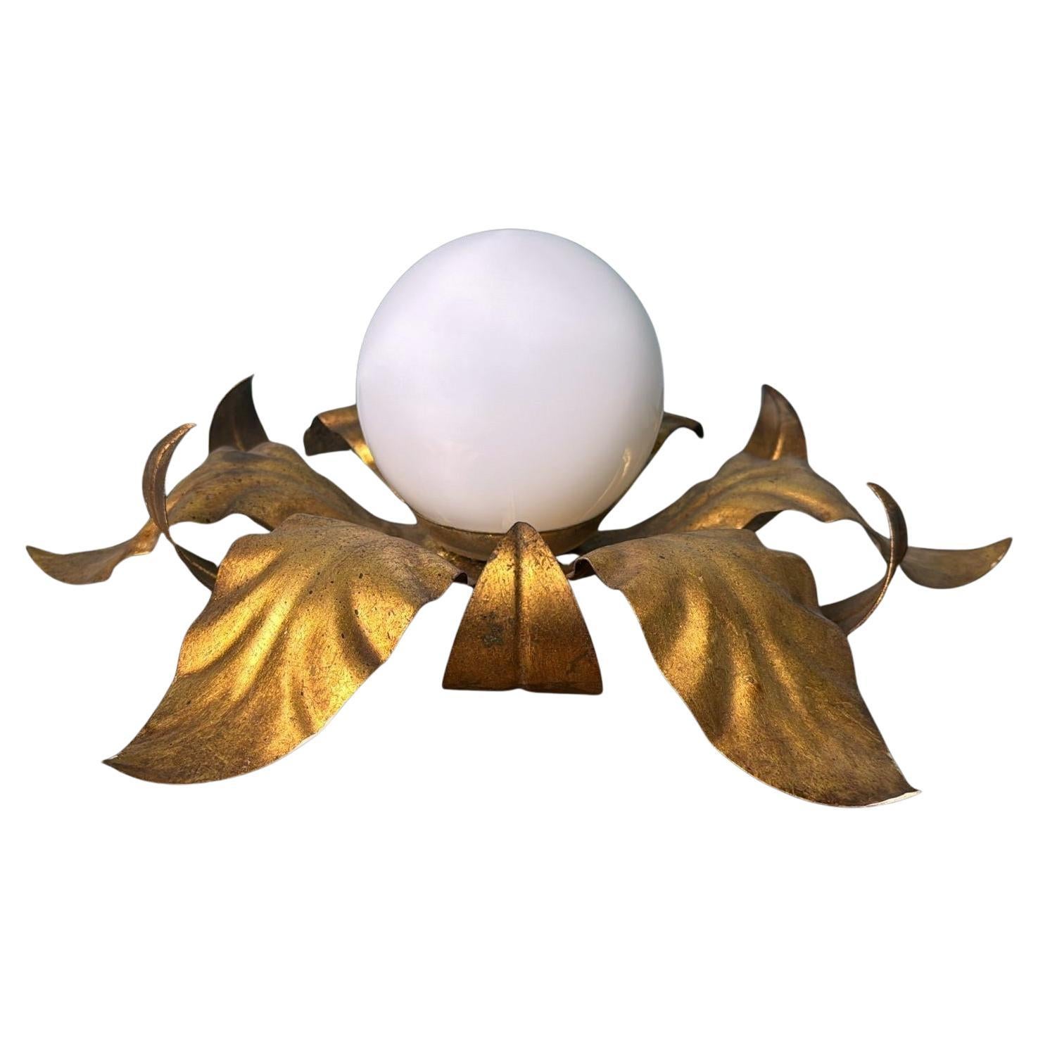 Elegante lampada da incasso, adatta per essere installata a soffitto o a parete, realizzata in Italia negli anni Cinquanta. È caratterizzato da una struttura scultorea in ottone dorato a forma di foglie vorticose, che circonda un globo centrale in