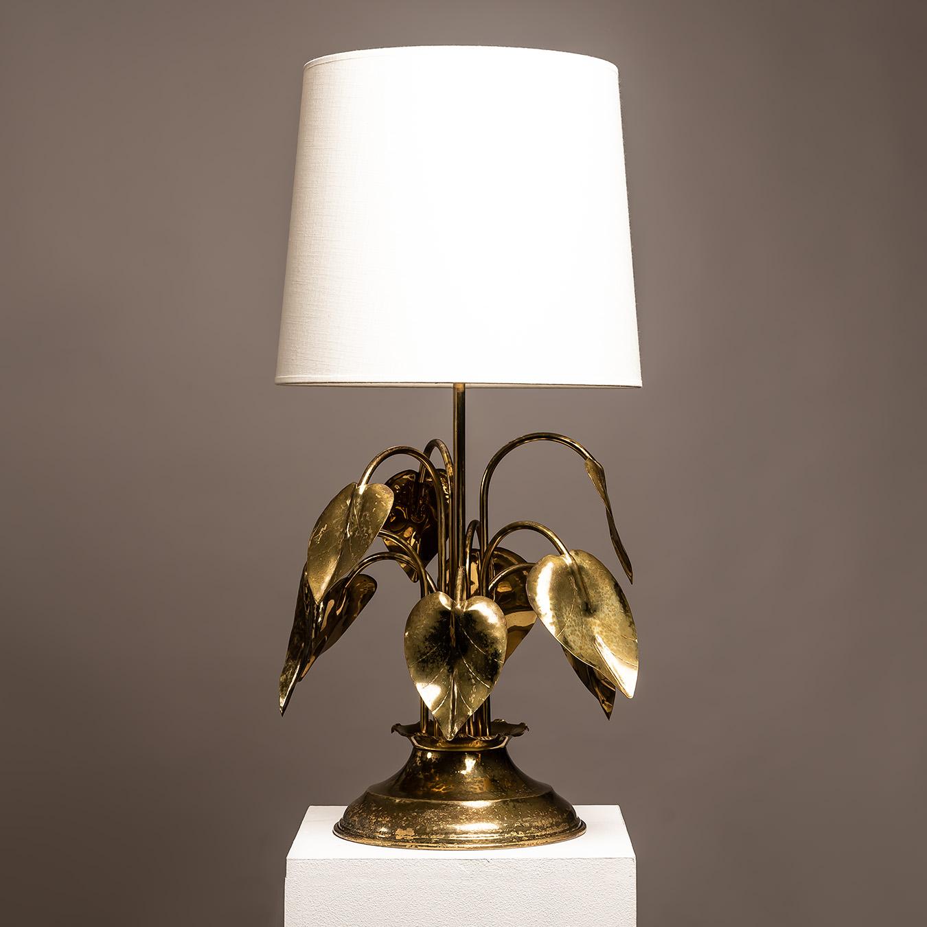 This striking Italian gilt brass table lamp, dating from the 1970s, captures the essence of Hollywood Regency glamour with its sculptural botanical motif. Handcrafted in Italy, the lamp is composed of gracefully curved stems and hammered anthurium