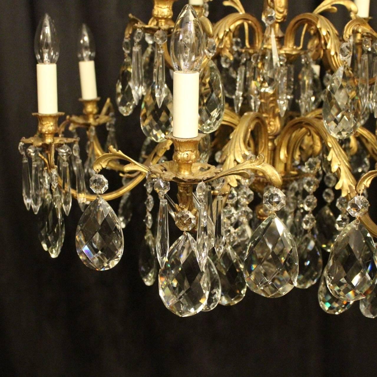 An Italian gilded cast bronze and crystal twelve-light double tiered antique chandelier, the eight and four-light leaf reeded scrolling arms with leaf bobeche drip pans and bulbous candle sconces, issuing from an ornate foliated central column with