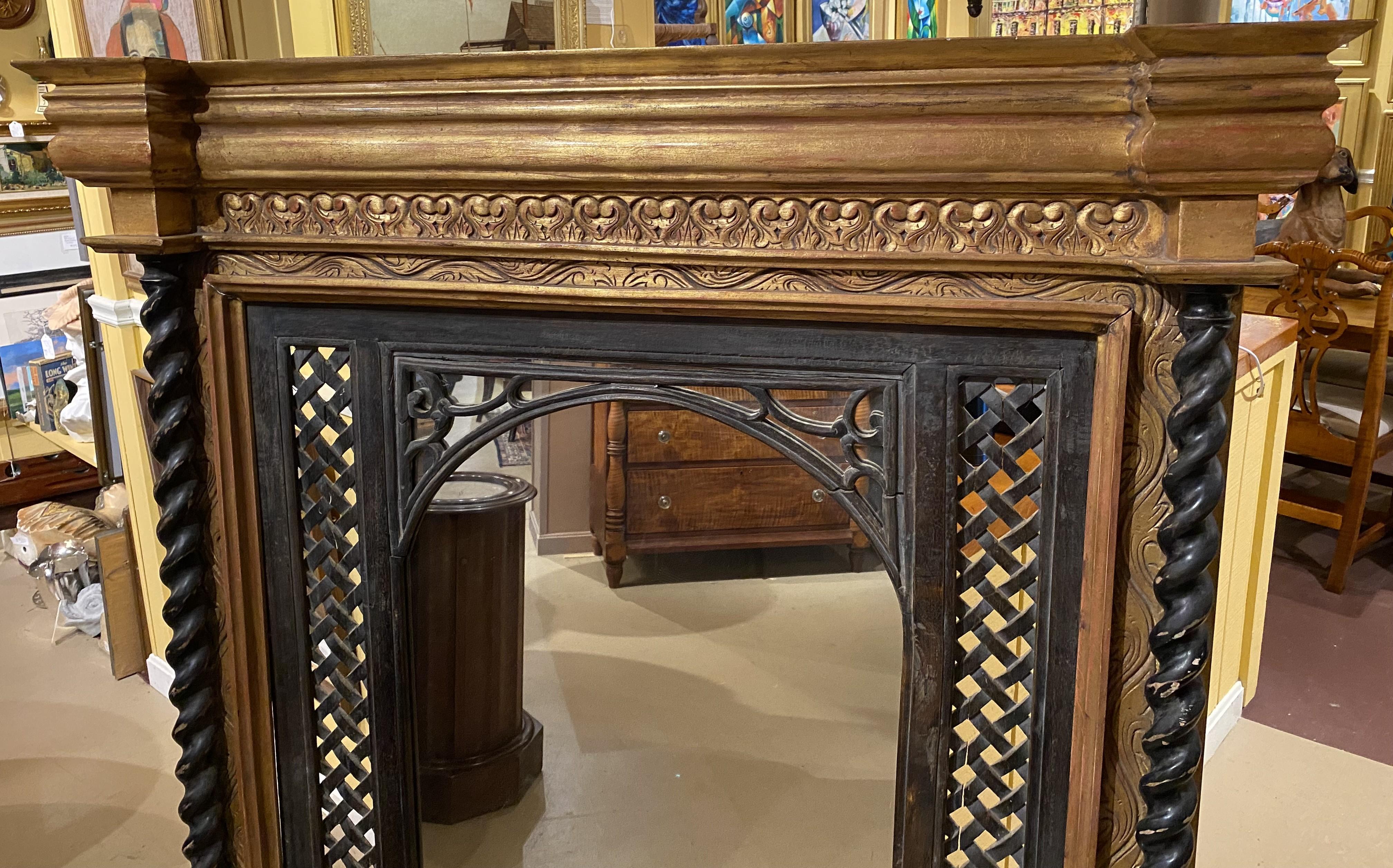 A fine vertical over mantle mirror with gilt scroll carved cornice and surround, accented with a  carved reticulated arch inset surround with lattice work flanking the mirror, along with carved full barley twist columns. The mirror is probably
