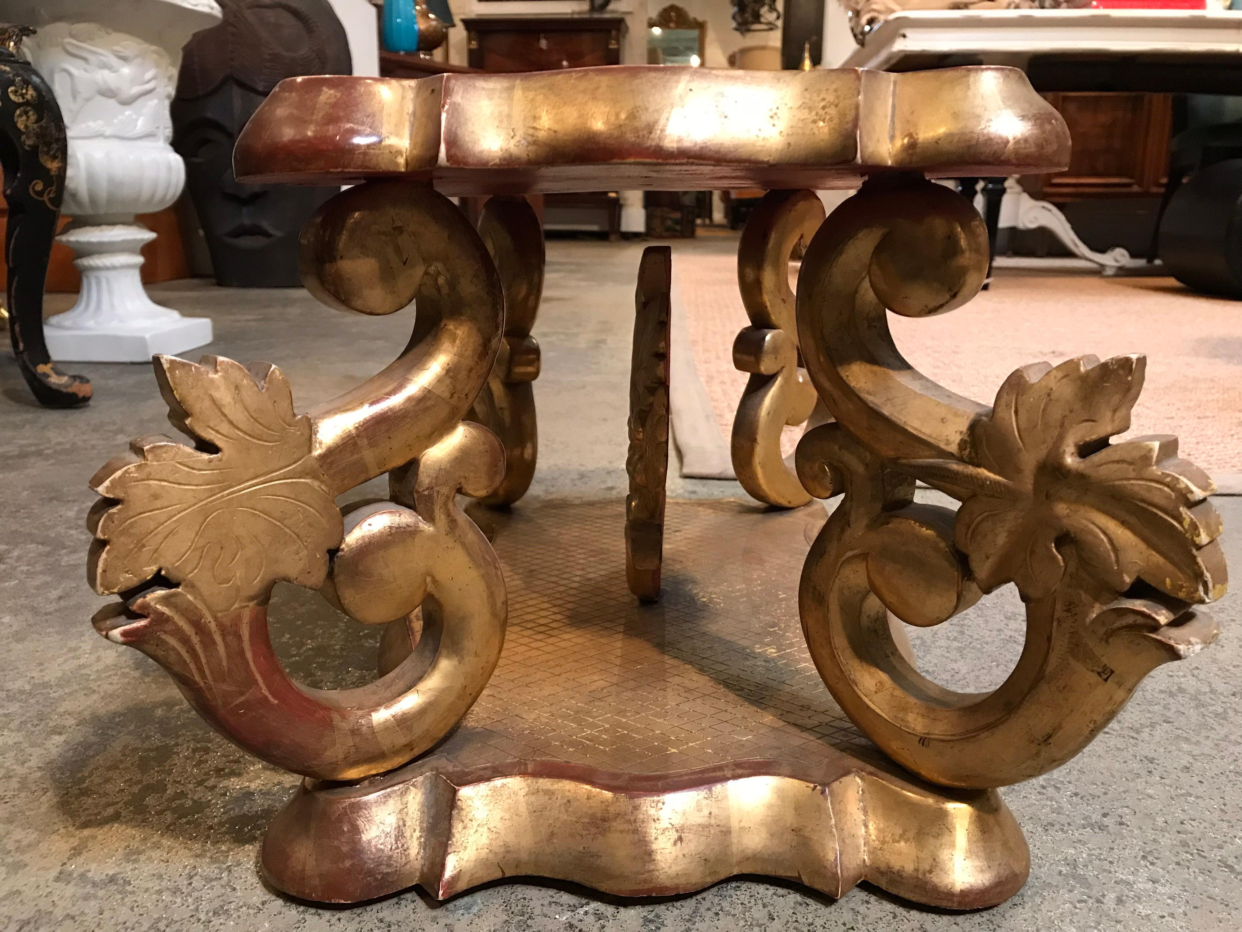 This short Italian stand is gilded in gold and was made sometime in the early 19th century. The 4 supports were carved in a serpentine form with a leaf on each one. It has something of a relic on the inside, also gilded. The top layer does come off