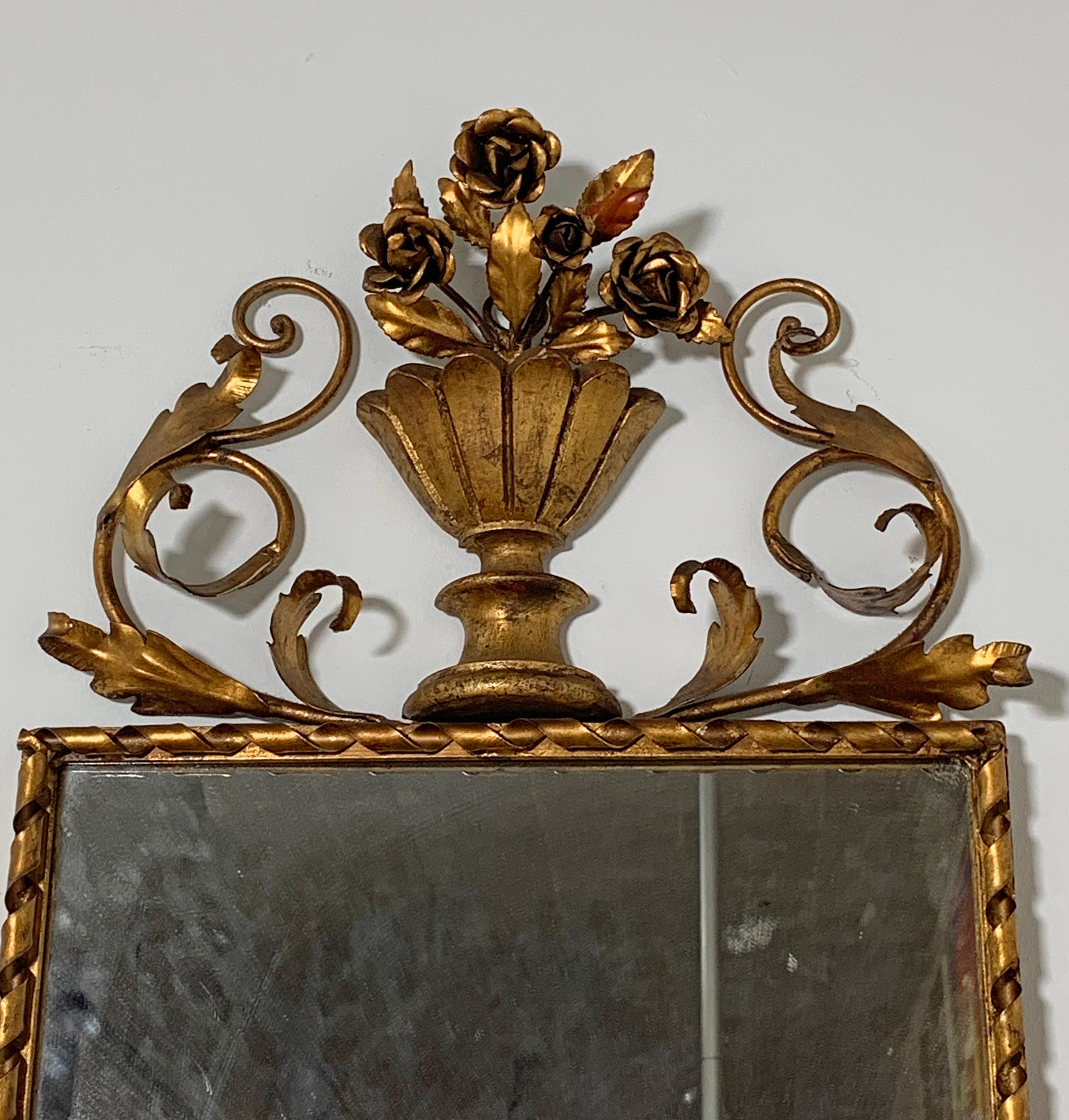 Miroir d'entrée italien en faïence dorée avec étagère en miroir, vers les années 1950. Le dessus est orné d'un cimier en forme d'urne et de guirlandes florales ; le dessous de l'étagère est décoré de feuilles et de fleurons ; deux bras rayonnants se