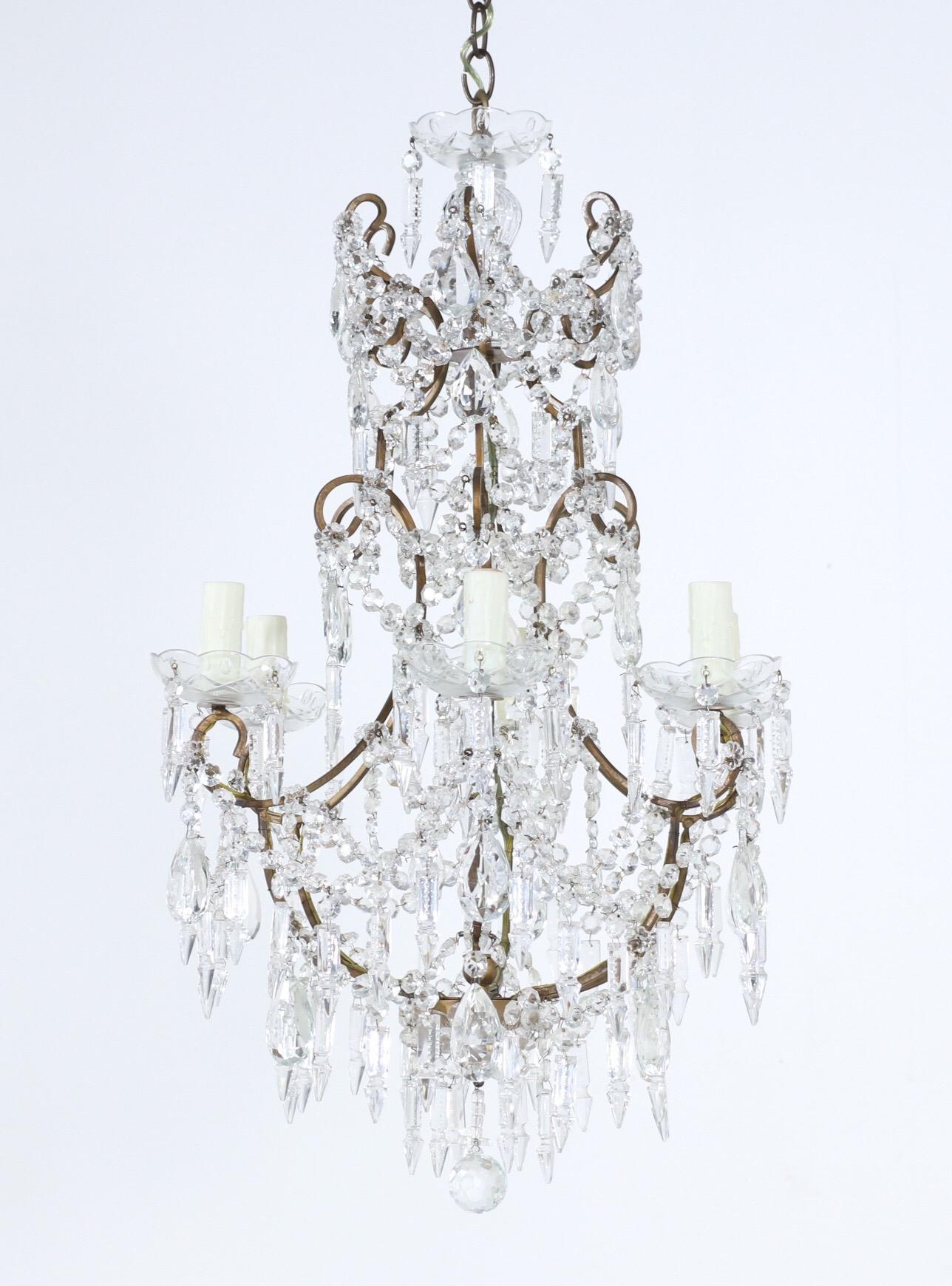Sparkling, Italian 1950s gilt-iron and crystal beaded chandelier.

The chandelier consists of a scrolled gilt iron frame which is loaded with crystal bead swags and faceted prisms in an assortment of shapes.

The chandelier is wired and in working