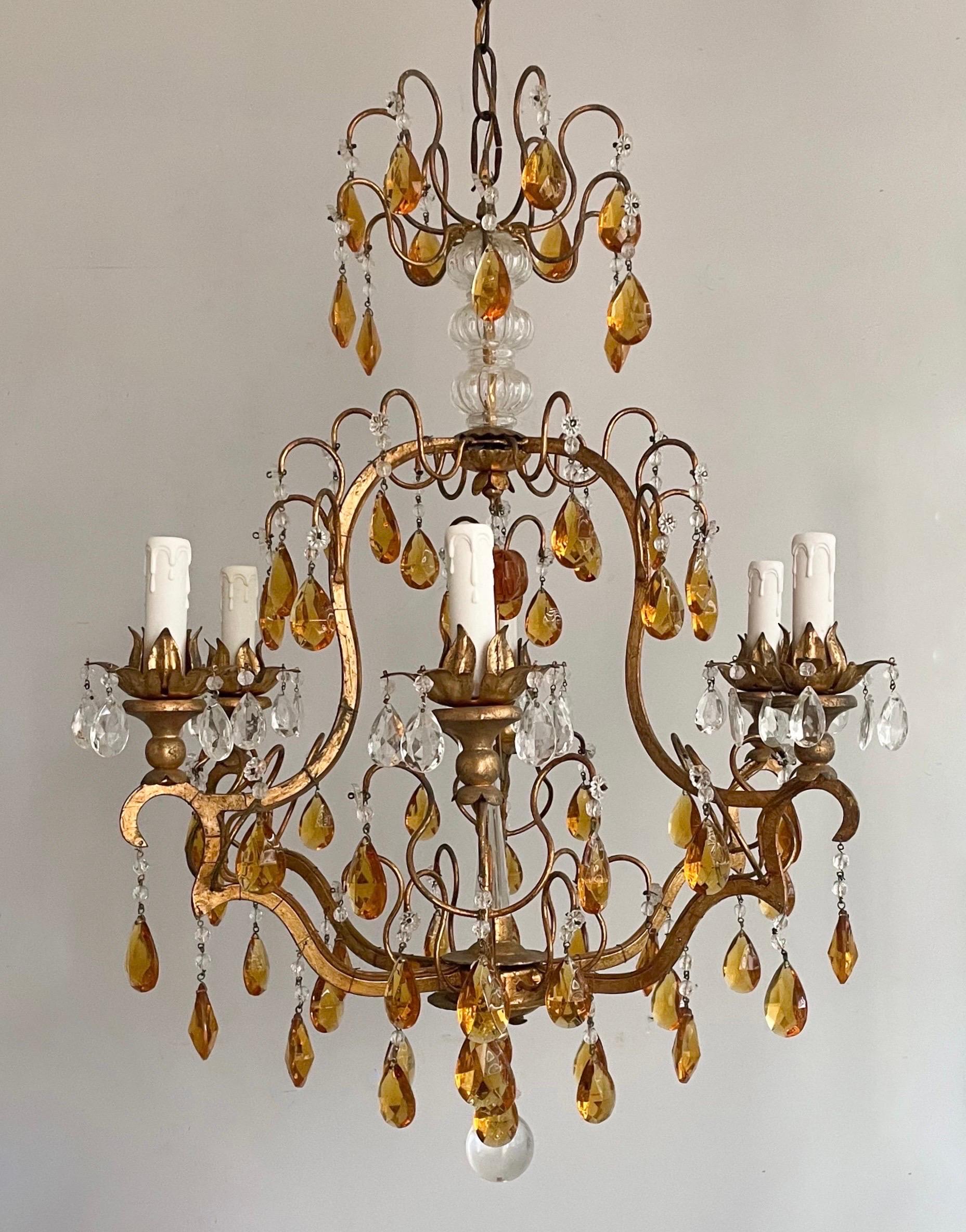 Gorgeous, 1960s vintage Italian gilt-iron and crystal beaded chandelier. 

The chandelier consists of scrolled iron frame in a pretty, hand-applied gilt finish and adorned with honey amber glass prisms. There are six lights set on gilt wood mounts.