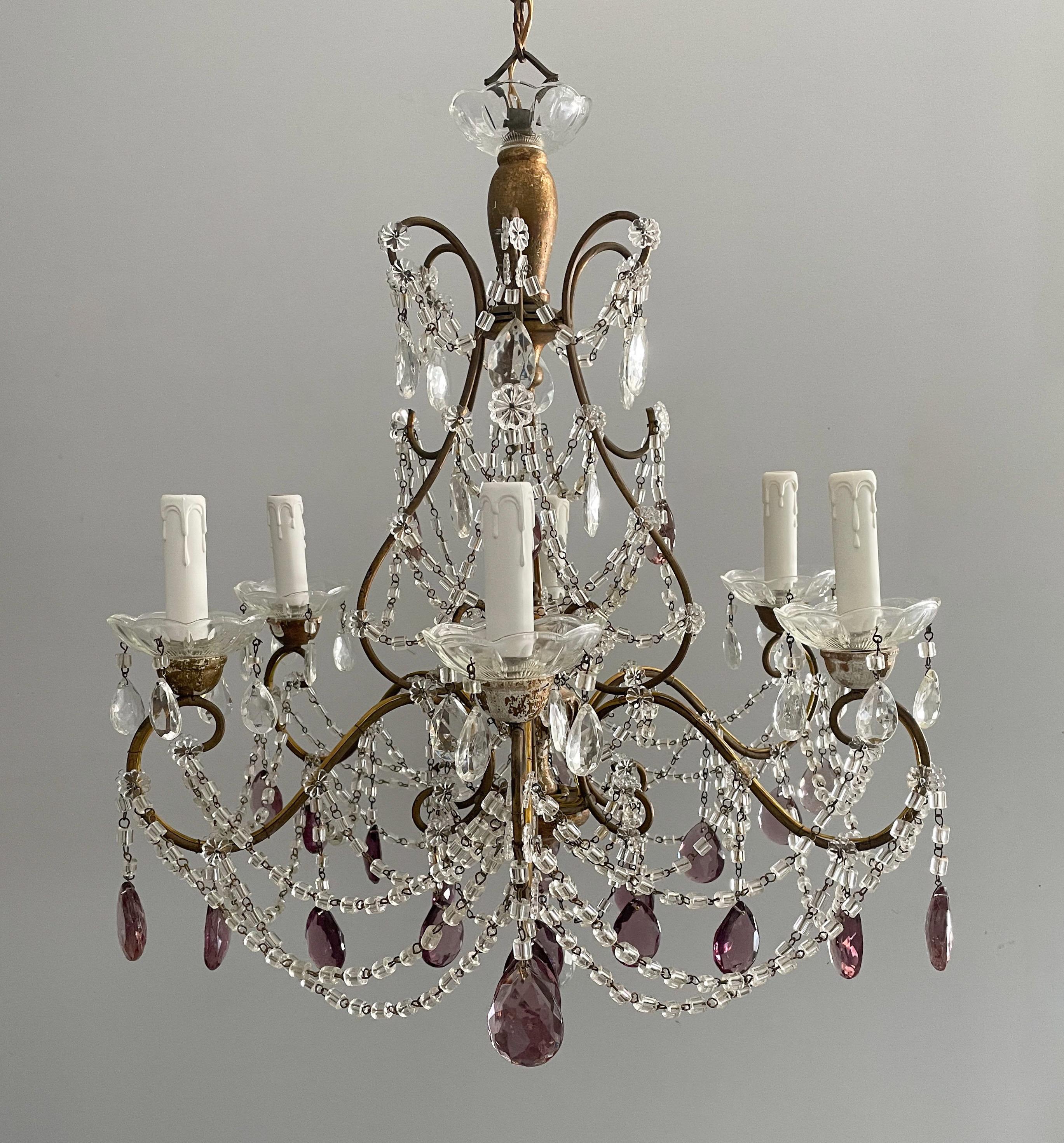 Exceptional, Italian 1920s gilt iron and crystal chandelier in the Louis XVI style. 

The chandelier consists of a scrolled iron frame decorated with carved gilt-wood accents, loads of “macaroni” glass beads and faceted prisms in various tones of