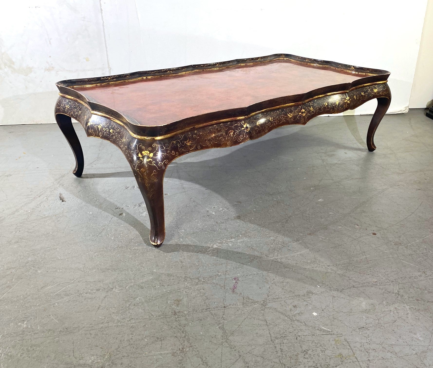 Table basse à décor de volutes dorées et laquées, pieds cabriole. Bord supérieur serpentin.