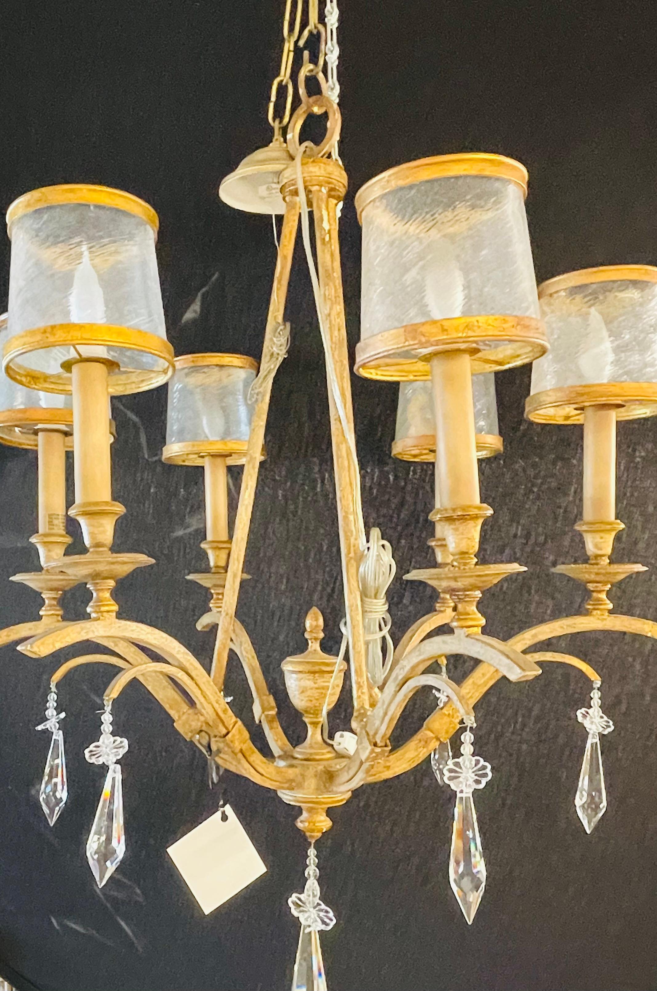 An Italian gilt metal and crystal chandelier with glass shades. This recently wired ceiling light brings glamour and glitz to any room that it would hung in. With its large hanging crystals statically placed to reflect light and shine this six-arm