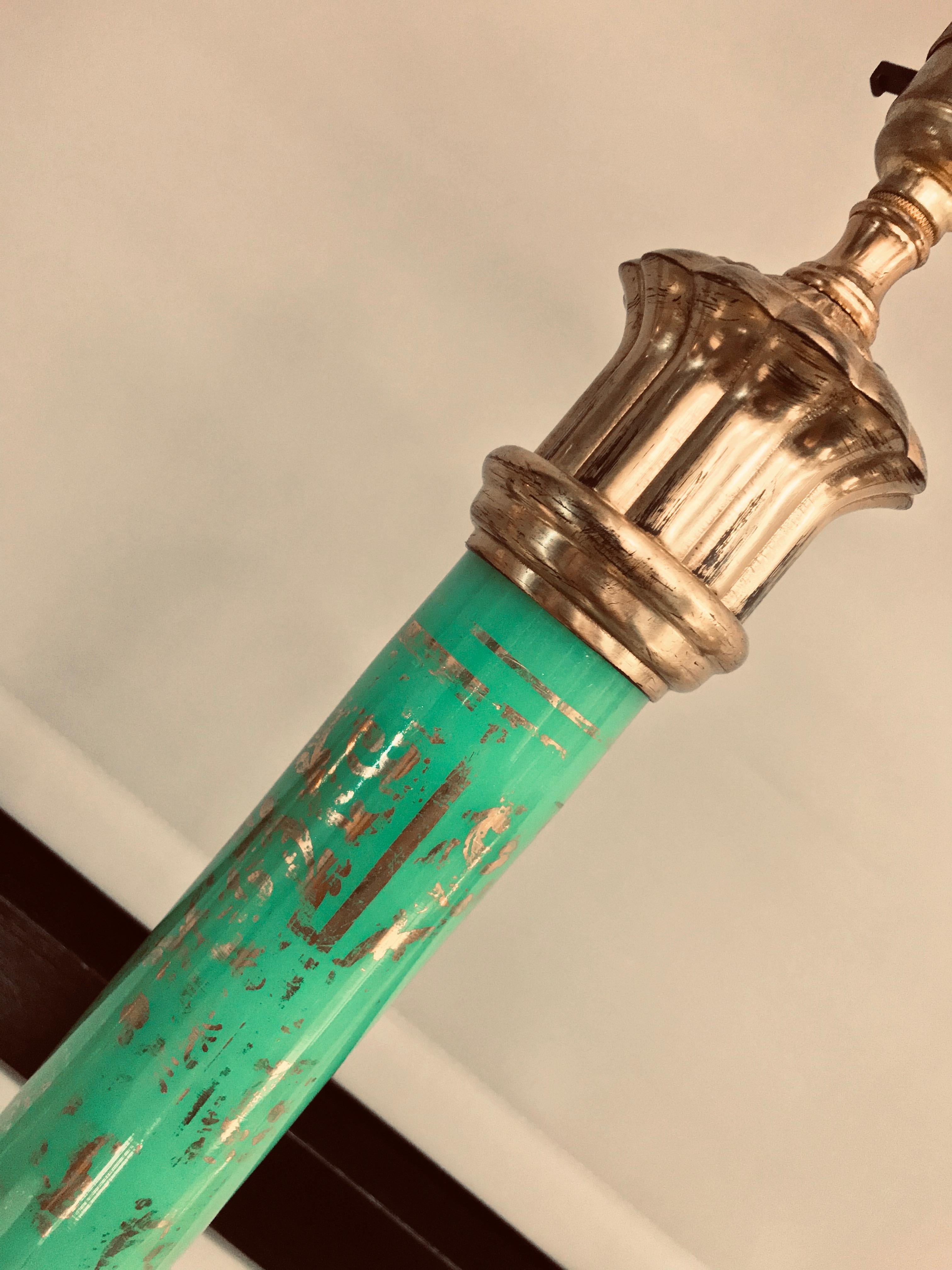 An Italian lamp in gilt metal with a green glass églomisé central shaft with traces of gold leaf.