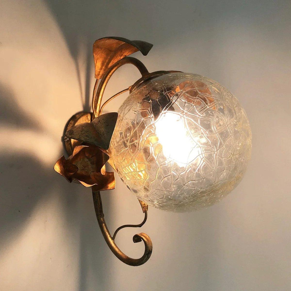 Magnifique paire d'appliques présentant une structure fantaisiste en métal doré avec un motif floral et des globes en verre à effet craquelé. Conçue et produite en Italie dans les années 1950. Son fonctionnement a été testé et il émet une belle