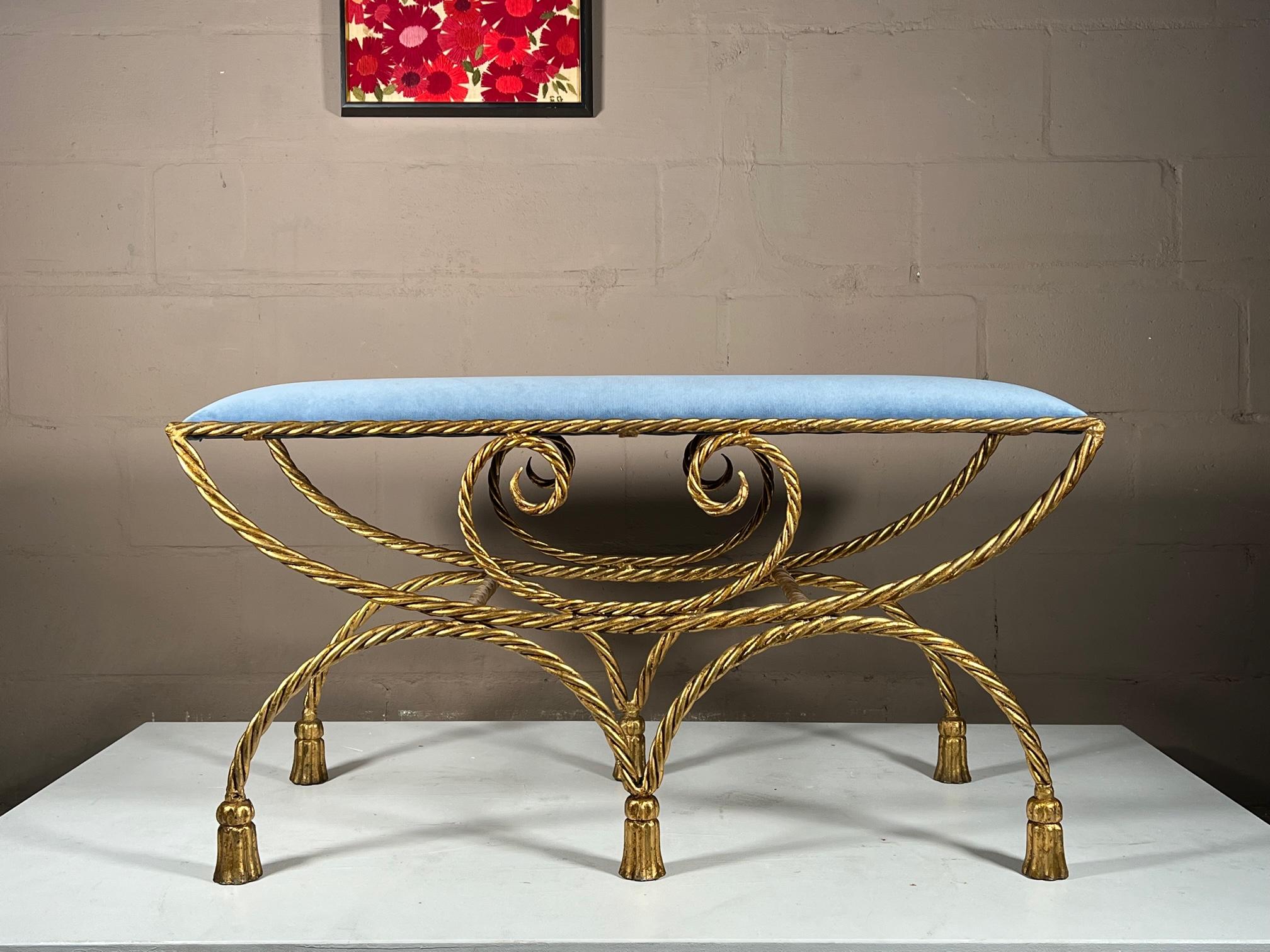 A great example of Italian Hollywood Regency bench. Gilt metal, twisted rope and tassel feet. Reupholstered in blue silk velvet-the color changes depending on light and angle. This bench is heavy and well made.