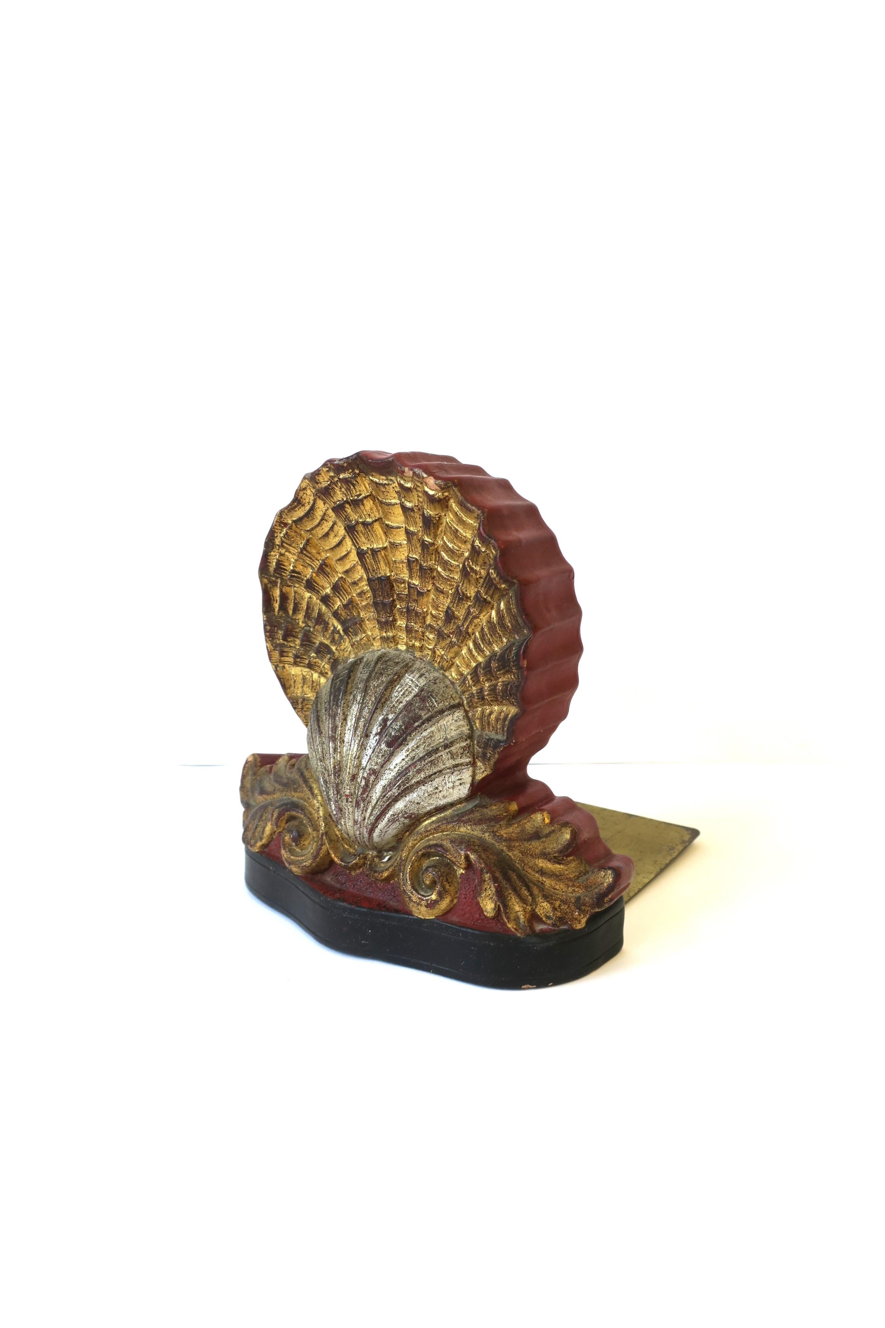 An Italian ceramic gold and silver scallop seashell bookend, circa early to mid-20th century, Italy. Bookend has both gold and silver gilt scallop seashells, two gold gilt acanthus leaves at base, red burgundy hue on side and back, black at base,