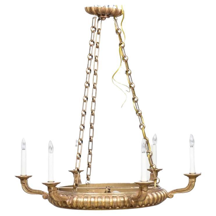 An Italian, gilt six arm Paul Ferrante chandelier. The beautiful light seamlessly marries classical opulence with contemporary design. Adorned with a sumptuous gilt composition frame, this exquisite lighting fixture is enhanced by a distinctive