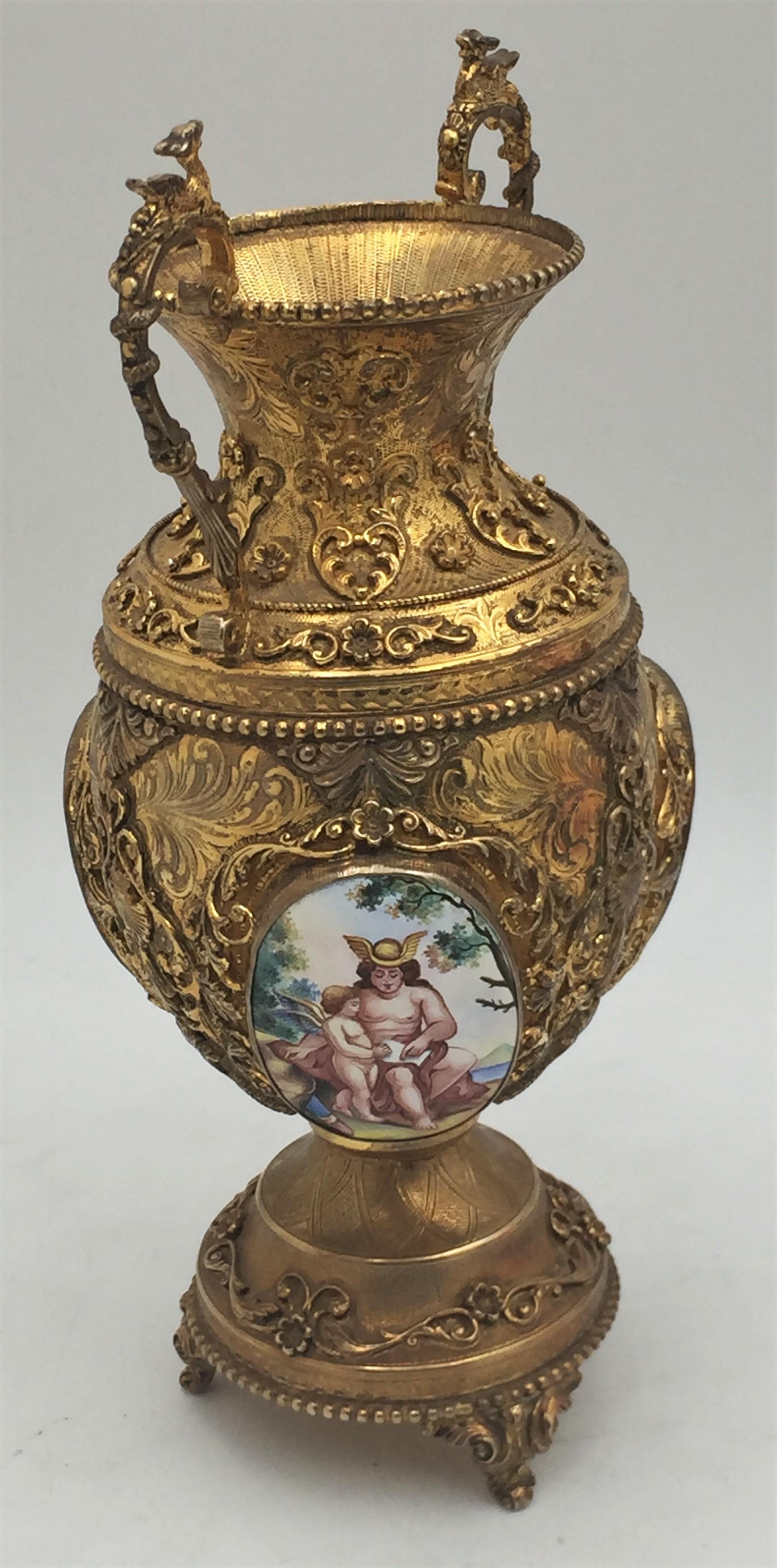 Vase italien en argent sterling doré, très décoratif avec des plaques émaillées, reposant sur 4 pieds, avec des ornements tourbillonnants sur le corps et la base, dans le style Buccellati. Il mesure 9 1/2'' de hauteur sur 4 1/2'' de profondeur au