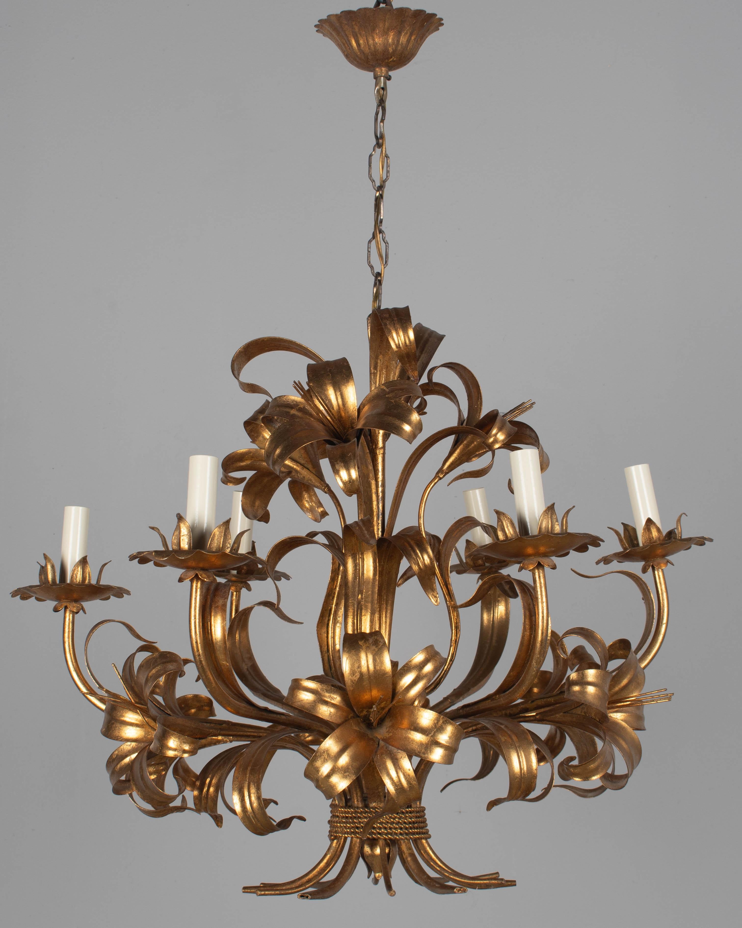 A Hollywood Regency style six-light gilt metal chandelier with tôle lily flowers. Original canopy and chain. Designed by Hans Kögl and made in Italy. New sockets and candle covers. In working order. Good original vintage condition with bright gilt.