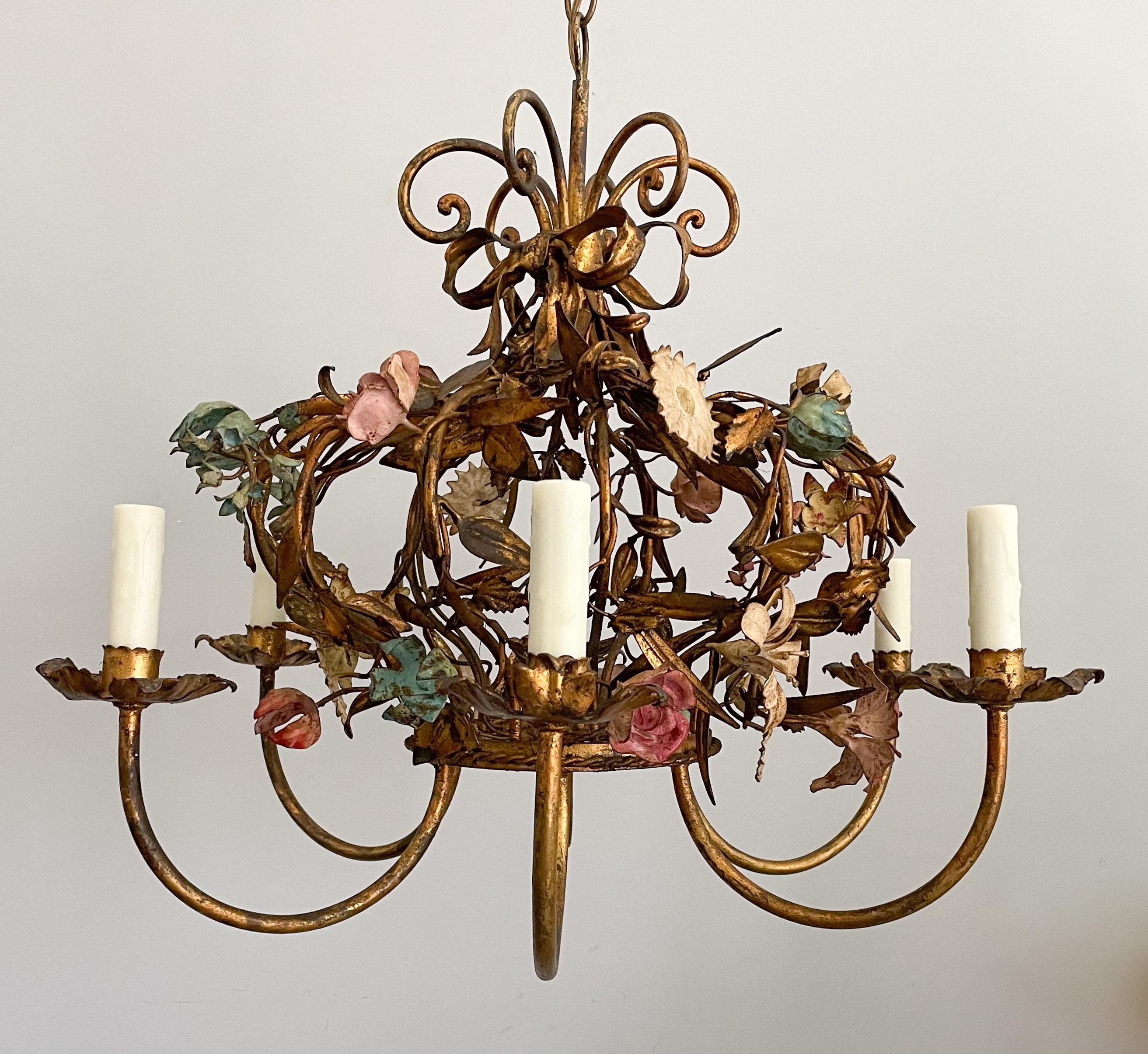 Beautiful, Italian 1940s gilt iron chandelier in the form of a crown made of flowers and foliage. 

The chandelier consists of a gilded iron frame shaped like a crown with an assortment of painted flowers held together by a gilded bow.

The