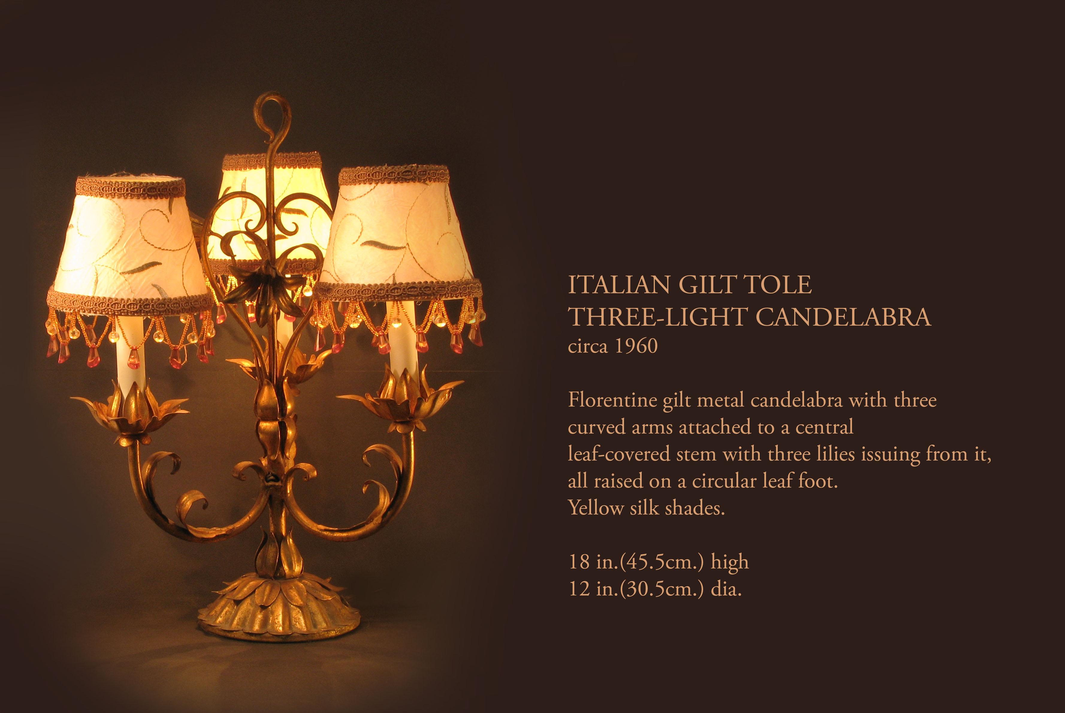 TOLE DORATE ITALIANE
CANDELABRO A TRE LUCI
Circa 1960.

Candelabro in metallo dorato di Florentine con tre
bracci ricurvi collegati a un'asta centrale
gambo ricoperto di foglie da cui escono tre gigli, il tutto sollevato su un piede circolare a
