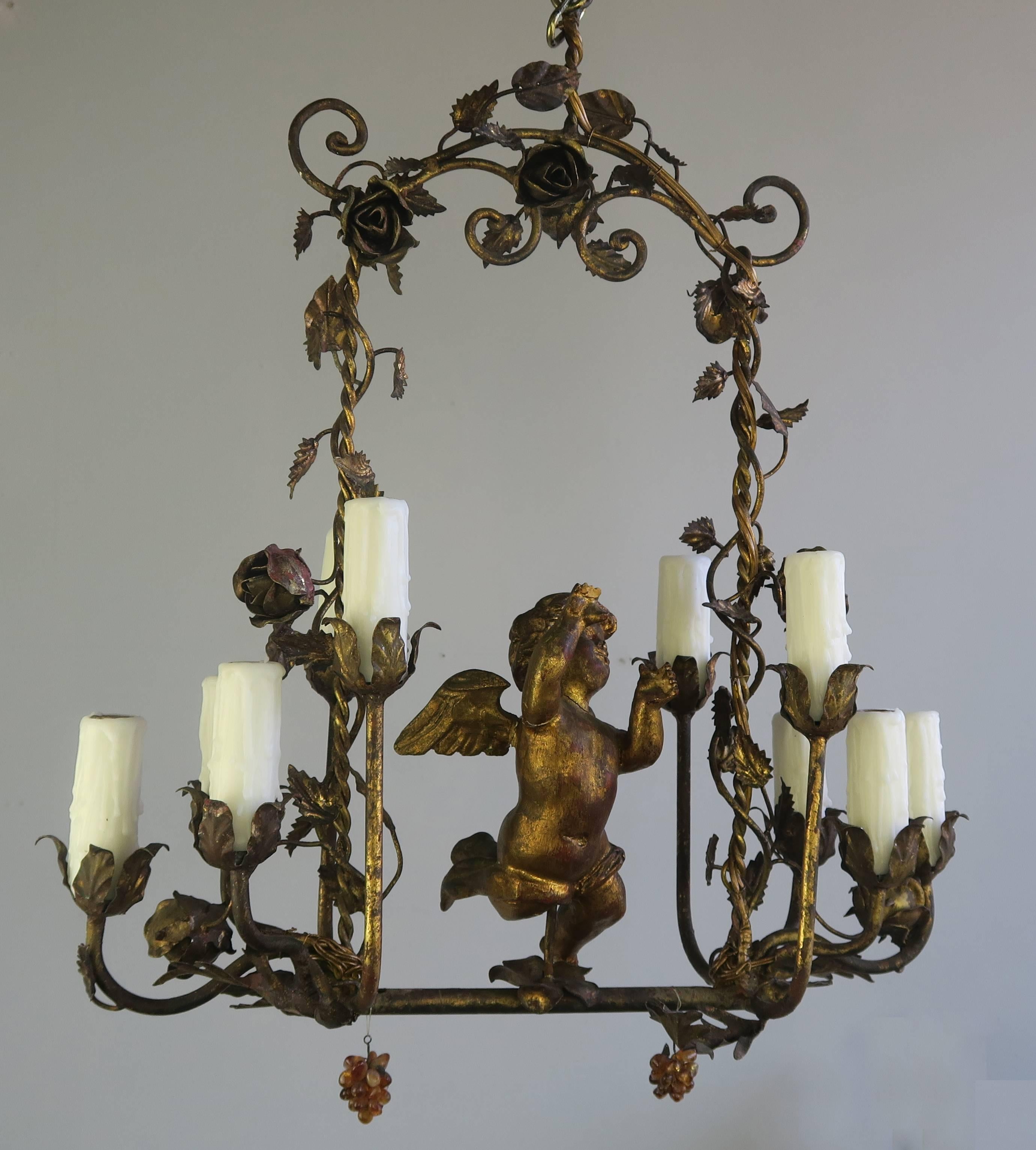 Unique Italian giltwood and metal cherub ten light chandelier. Fine gilt metal flowers and leaves make a beautiful arch over a giltwood cherub. The fixture is newly wired with drip wax candle covers. Includes chain and canopy.