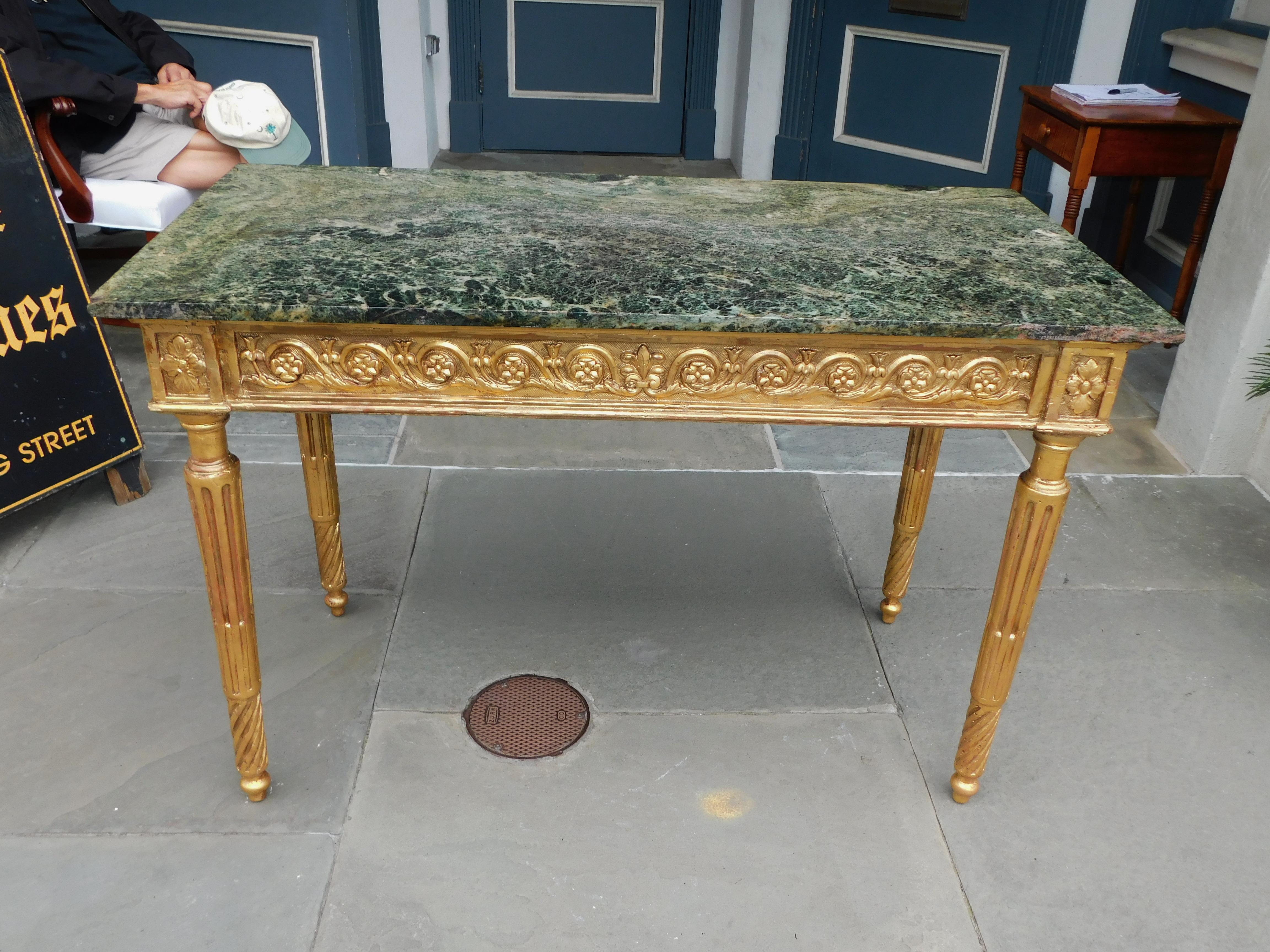 Italian gilt wood and gesso rectangular marble top console table with a articulated foliage medallion skirt, and resting on fluted spiral legs with ball feet. Console table retains the original marble. Late 18th Century.