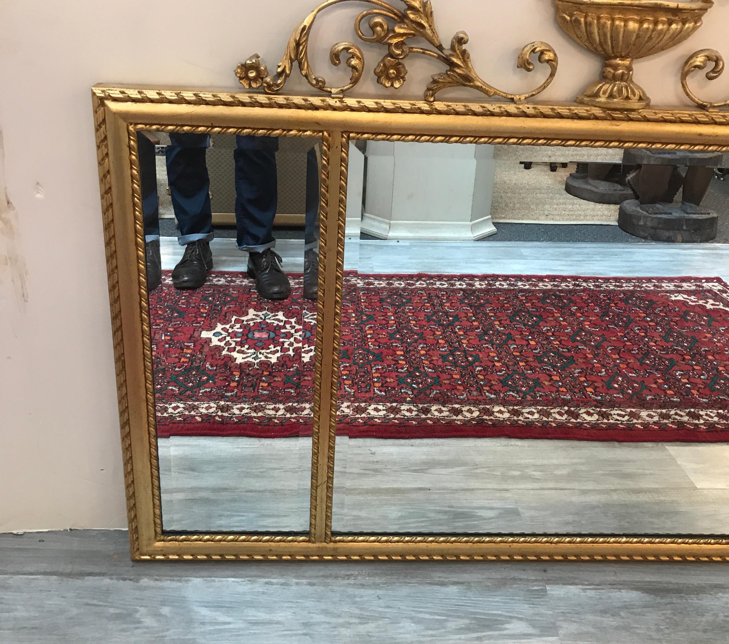 An elegant Italian made giltwood mirror by Labarge. The three section mirror with beveled edges surrounded by an elaborate English Adam Style frame. The urn pediment with scrolling foliate details with gadrooned edge on the edges.
