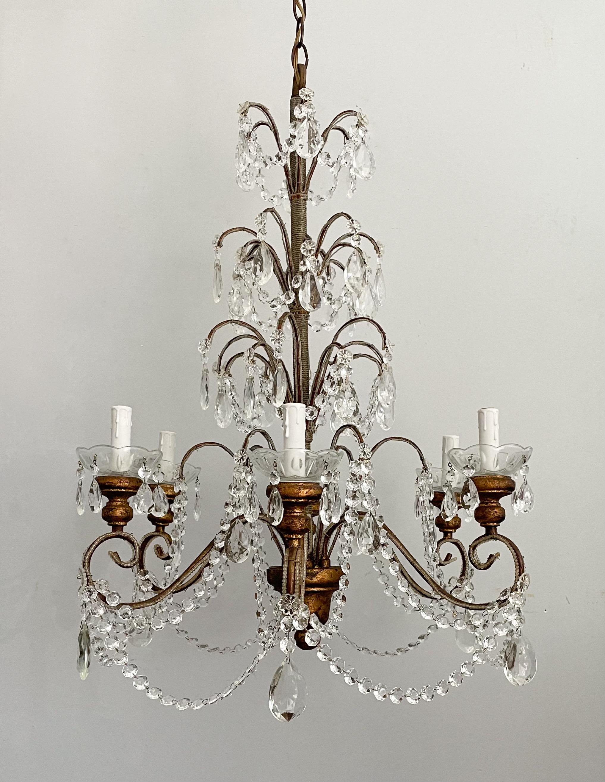 Beautiful, Italian gilt-iron and crystal chandelier.

The chandelier features a gilded iron frame wrapped with tiny glass beads, giltwood components and faceted crystal decorations.

The chandelier is wired and in working condition, it requires