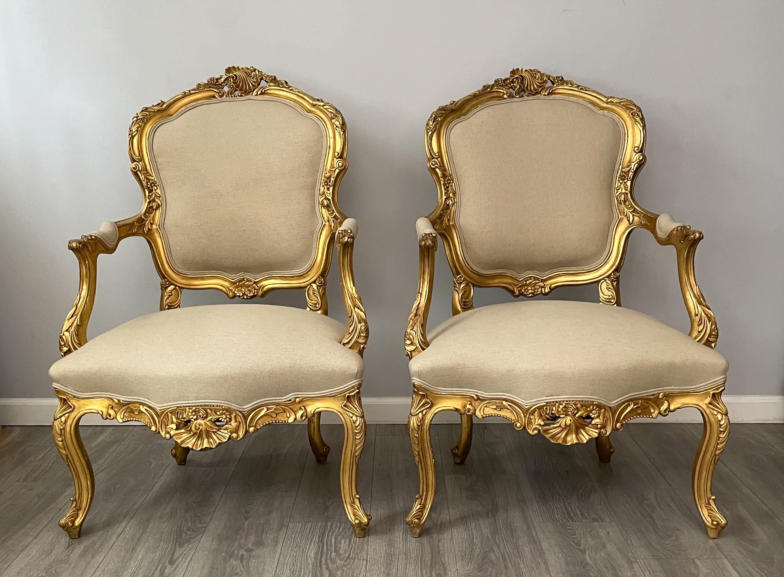 Fabuleuse paire de fauteuils italiens des années 1940 de style rococo. 

Chacune des chaises se compose d'un cadre en bois doré magnifiquement sculpté et d'un revêtement en lin belge neuf. 

Perte mineure de la dorure correspondant à l'âge. Les