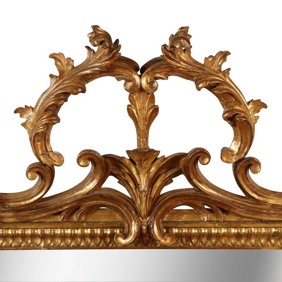 Miroir italien en bois doré sculpté avec des détails en forme de volutes et un plateau ouvert et ornemental sculpté.