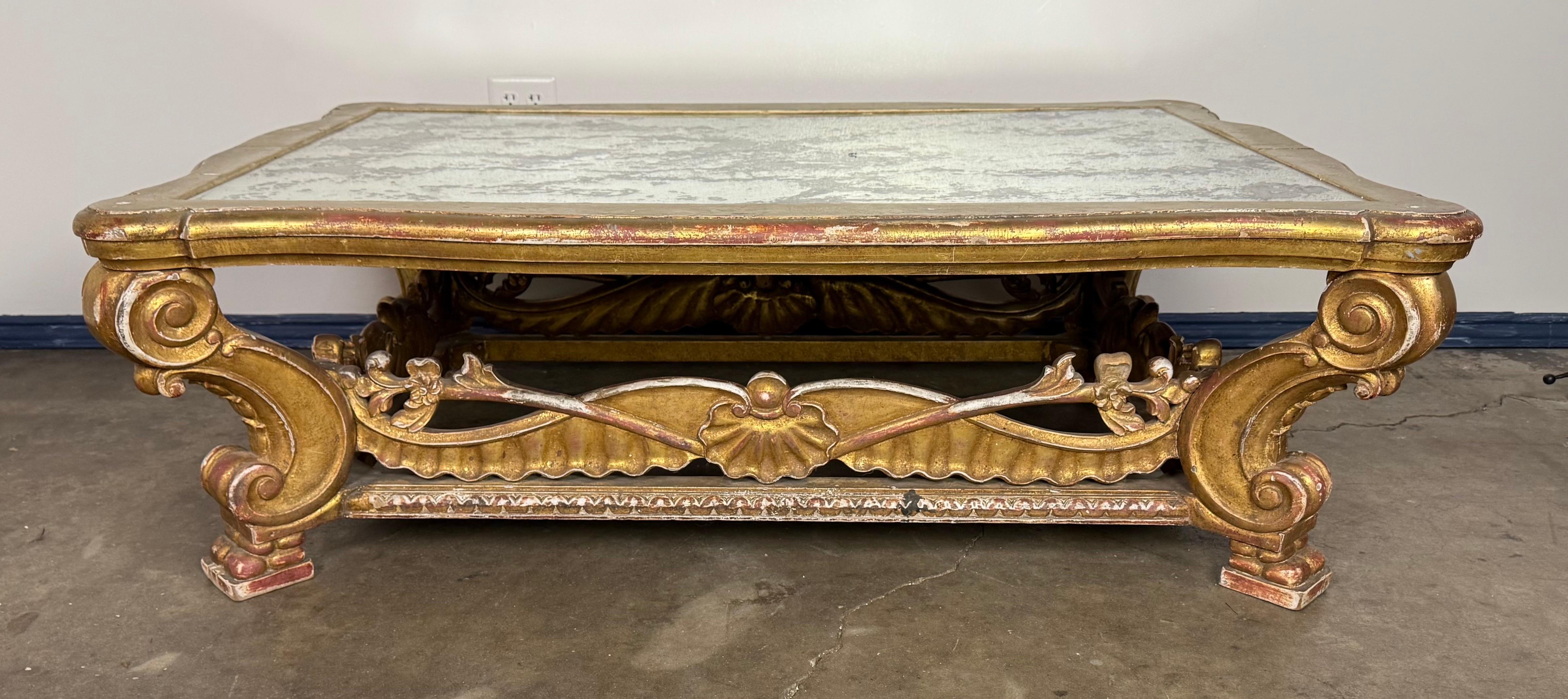 Dieser italienische Couchtisch aus Goldholz strahlt mit seiner kunstvollen Verarbeitung und seinem zeitlosen Charme Opulenz aus der Alten Welt aus. Der geschnitzte Holzsockel weist Akanthus-Details, Muschelmotive und florale Akzente auf, die in