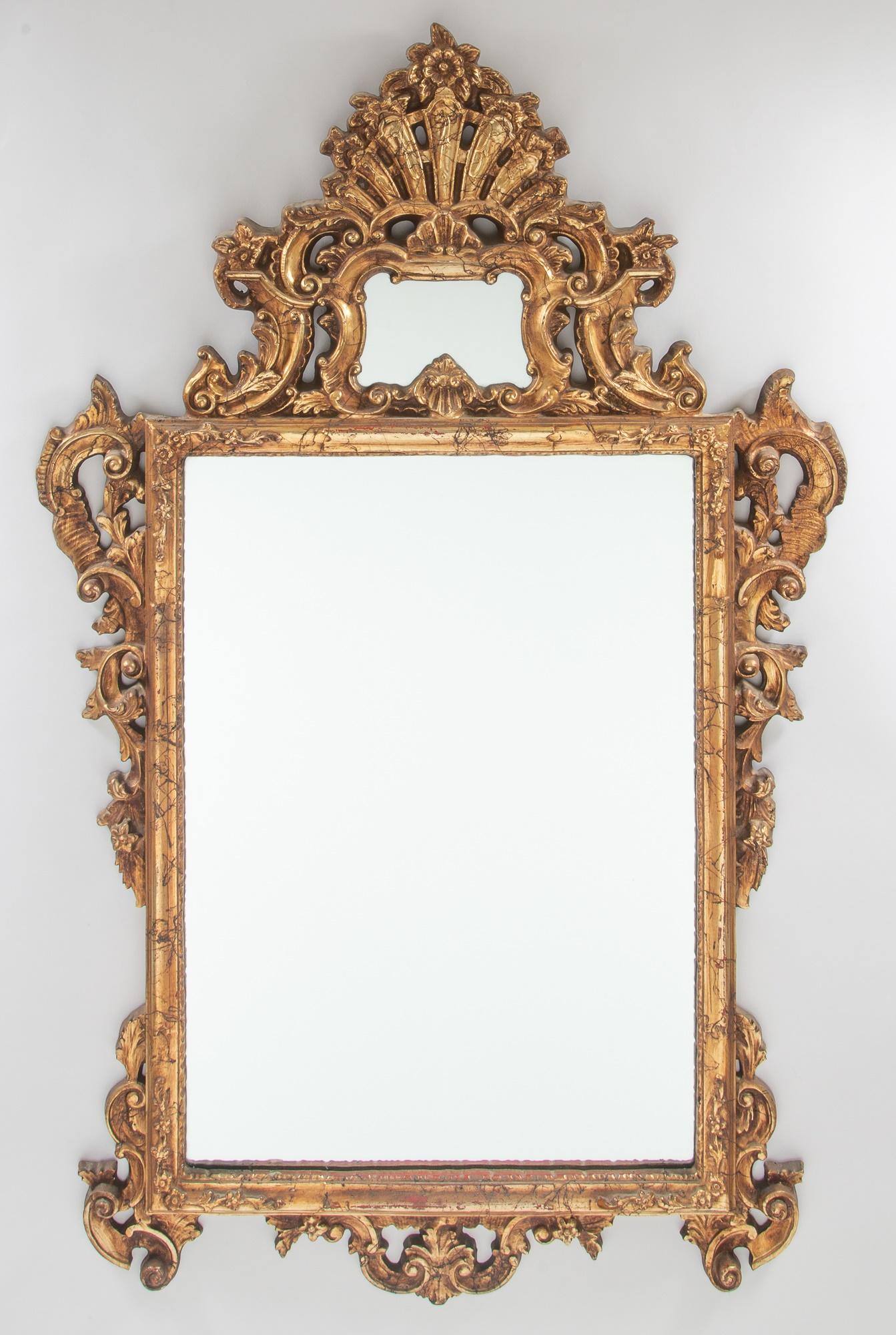 Verleihen Sie Ihrem Zuhause einen Hauch von Eleganz und Opulenz mit diesem atemberaubenden, handgeschnitzten und vergoldeten Kaminsims-Spiegel aus der Mitte des 20. Jahrhunderts im Rokoko-Stil. Der Spiegel wird von einem exquisit verzierten Rahmen