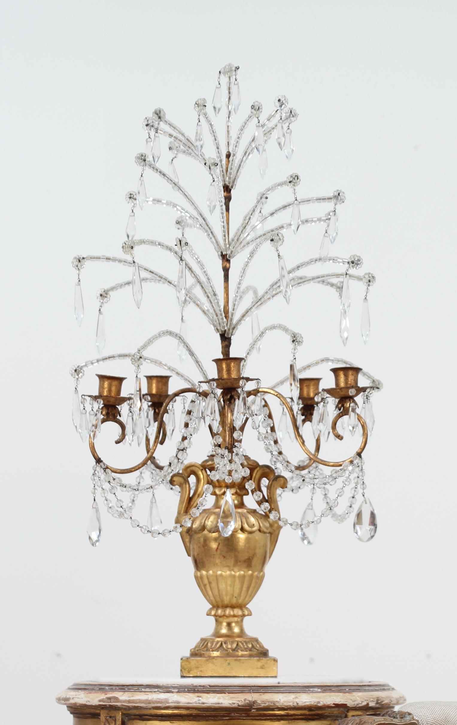 Candélabre ou girandole de style baroque en bois sculpté doré, fer et cristal, du début du 20e siècle.

Cette girandole de belle facture se compose d'une série de branches en perles de cristal qui partent d'un cadre en fer doré et qui sont montées