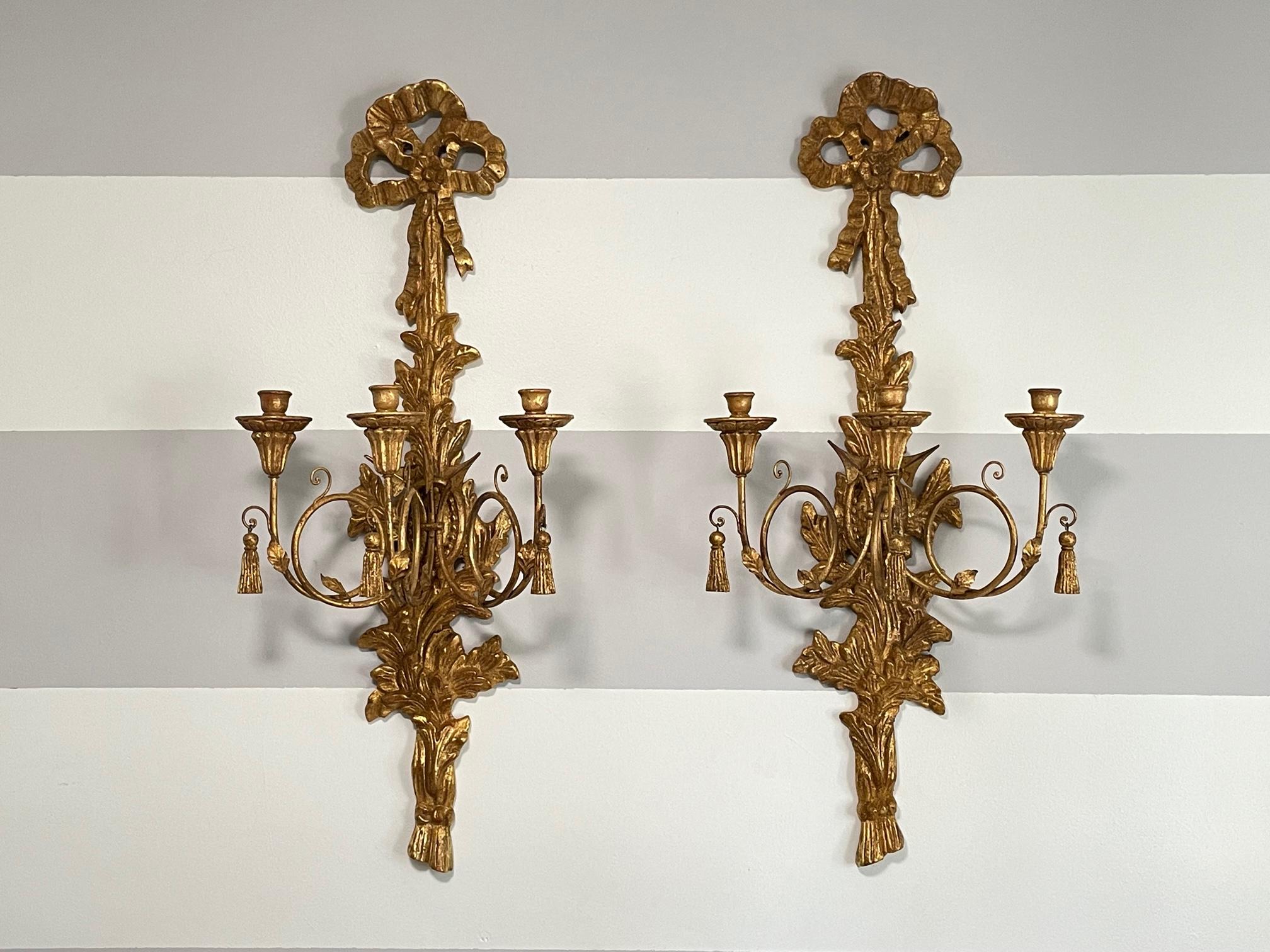 Pair of Italian giltwood candle sconces feature 3 arms and carved in a motif of acanthus leaves, arrows, and bows. Marked 